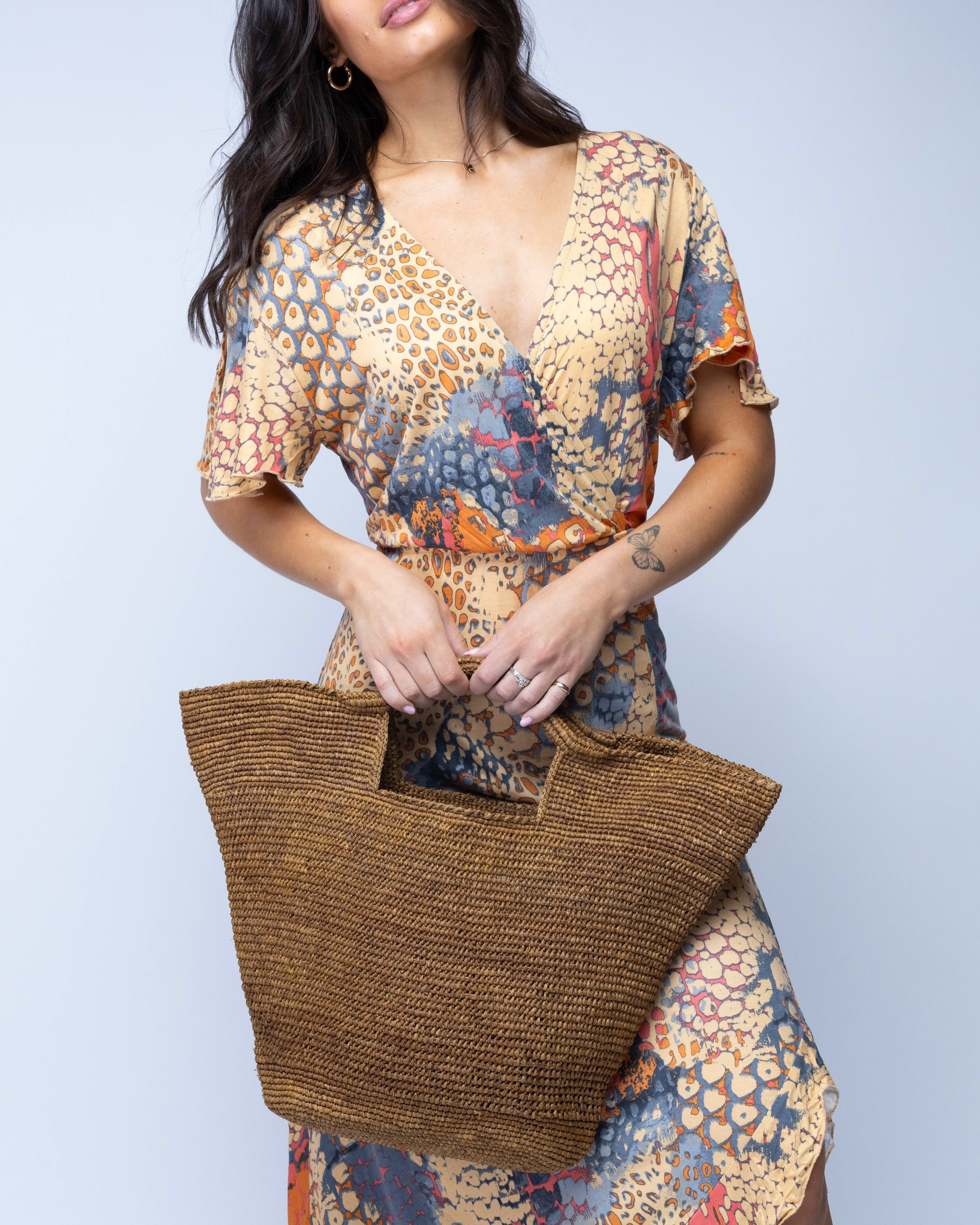 Model wearing ConCon Crochet Straw Basket handmade woven raffia palm fiber in a solid hue of cinnamon/tobacco/dark/brown making a textured link pattern handbag tote - Shebobo