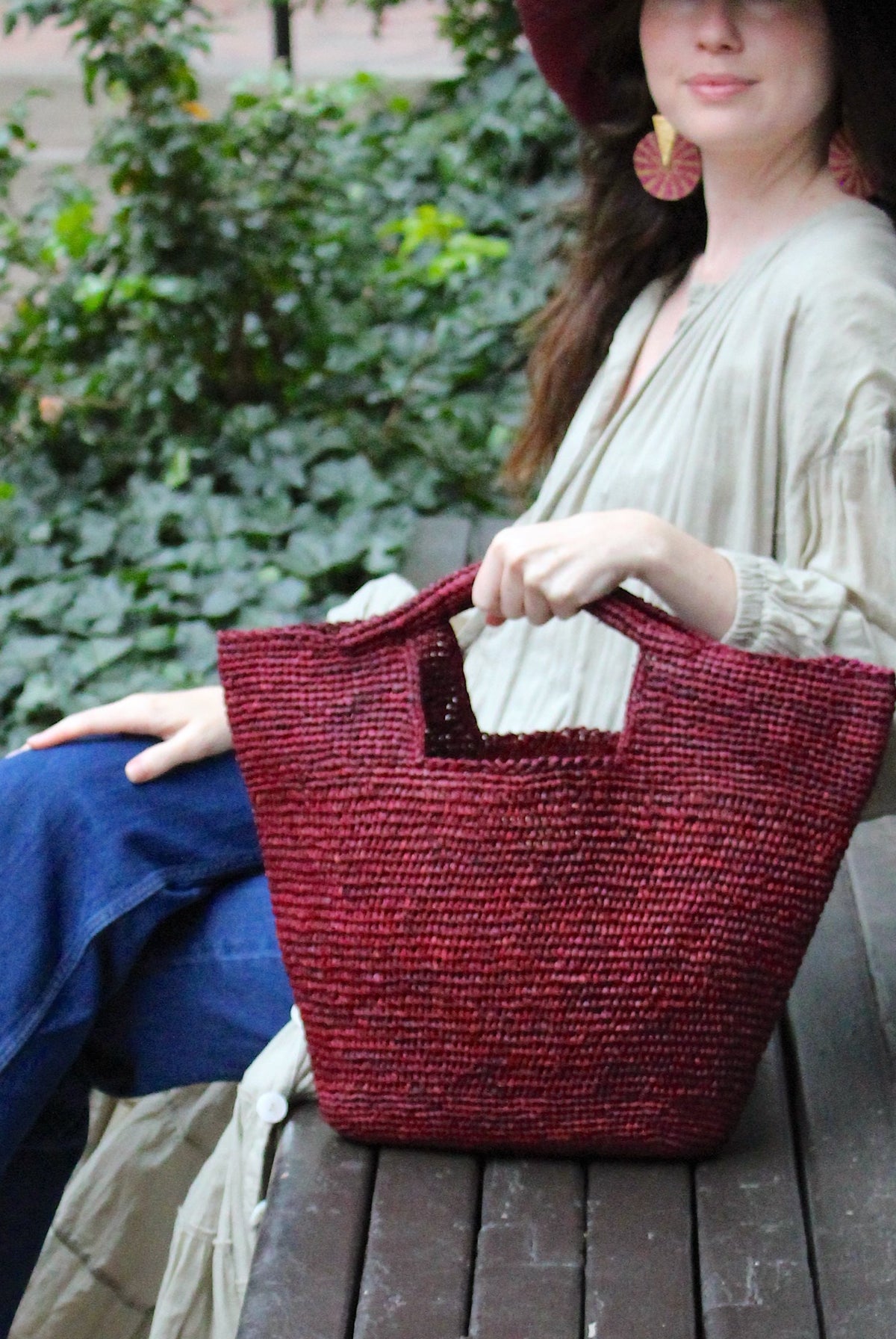 Model wearing ConCon Crochet Straw Basket handmade woven raffia palm fiber in a solid hue of umberwine bordeaux/claret/deep/dark/purple/red making a textured link pattern handbag tote - Shebobo