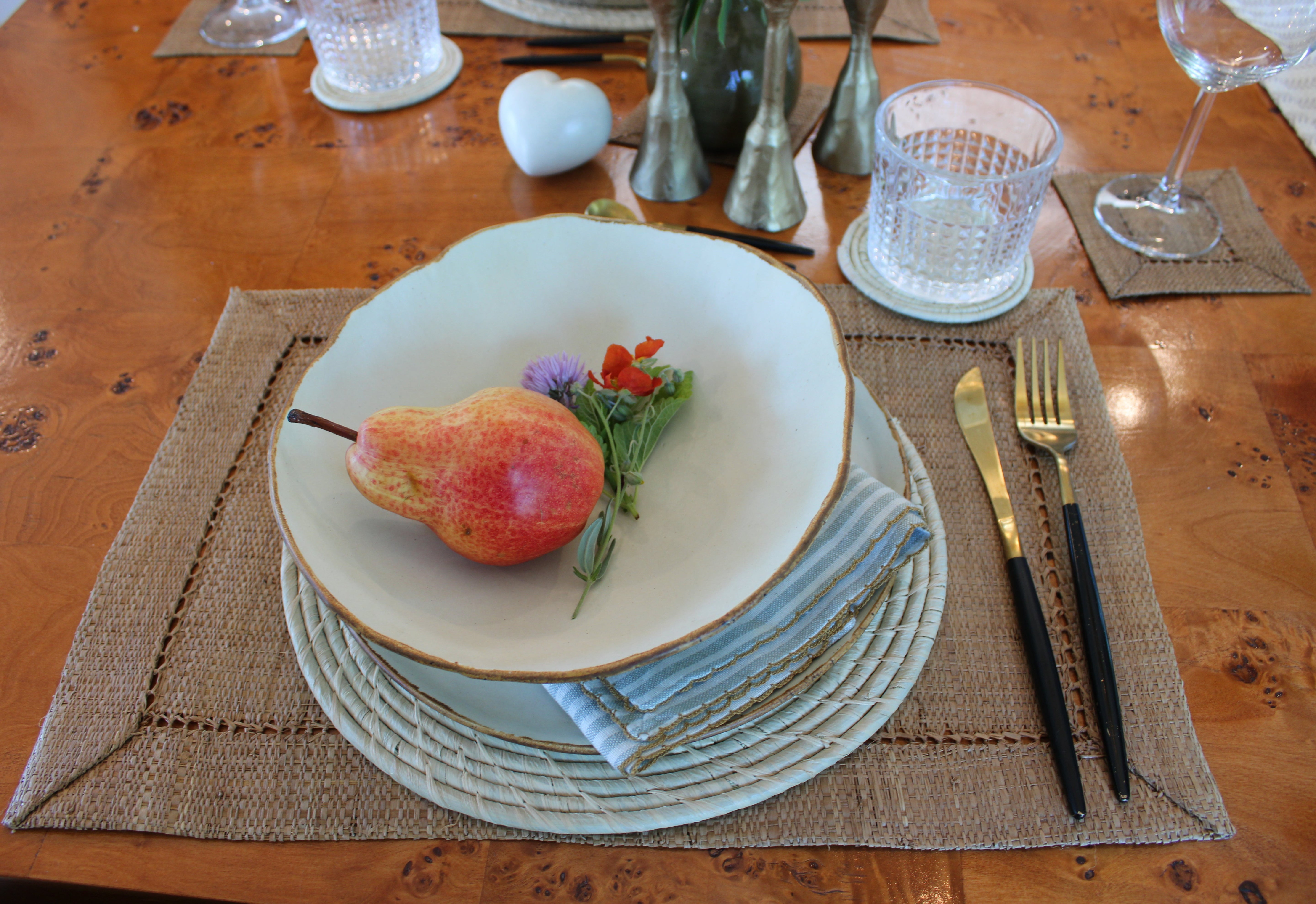 Table setting lifestyle view Dabu Round Two Tone Swirl Raffia Straw Coasters & Placemats Set of 6 handmade natural raffia palm fiber in a crochet loop disc technique creating concentric circular stripe pattern of texture in a solid hue of natural straw color with matching knotted spiral swirl weave sets of six placemats or coasters - Shebobo