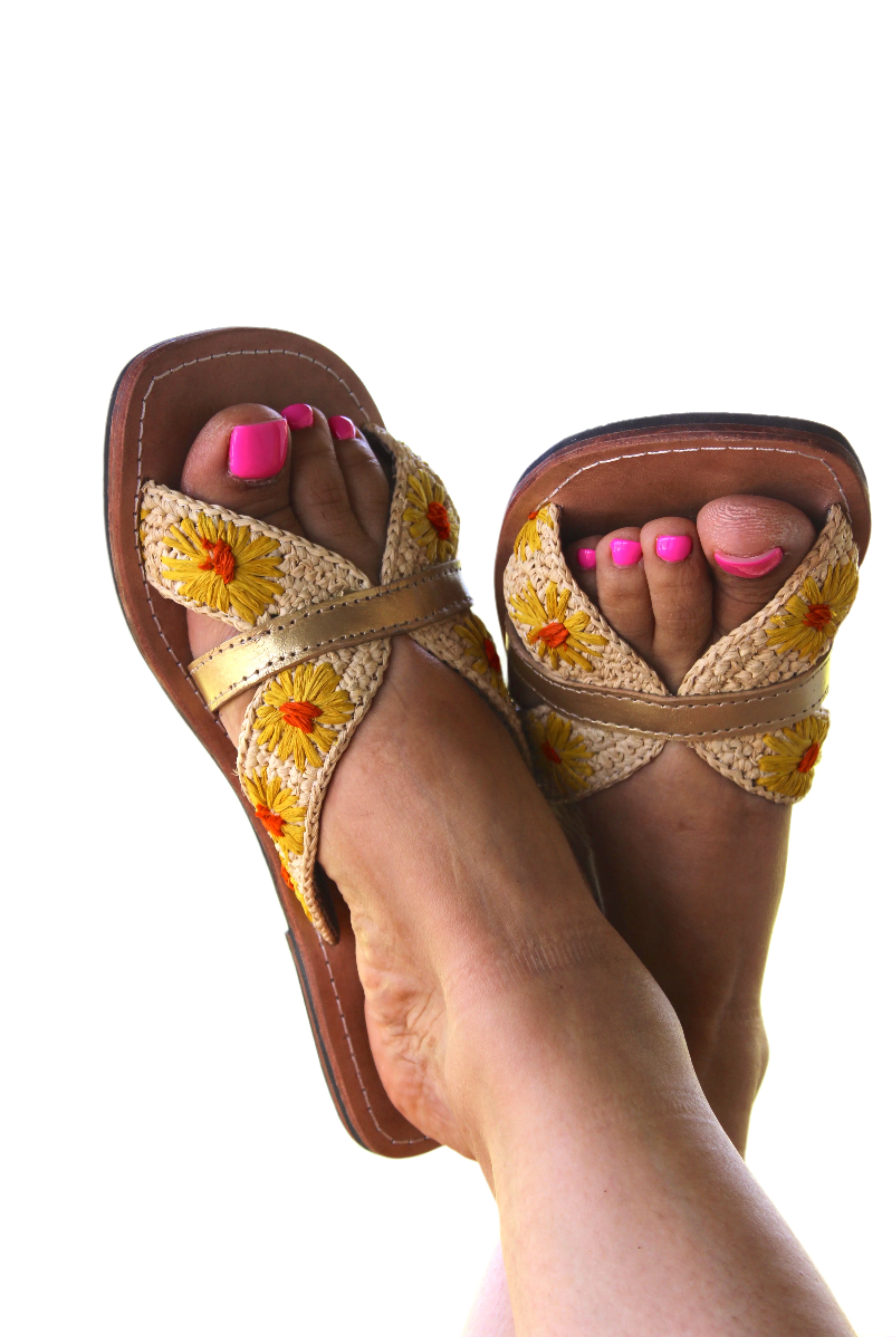 Model wearing Daisy Crochet Straw & Leather Sandal with Flower Embroidery & Metallic Detailing handmade crochet natural raffia palm fiber in a solid hue of natural straw color in two bands with saffron yellow petals and coral orange/red centered embroidered flower pattern wrap around the top of the shoe with a band of metallic gold across the top summer sandals shoes - Shebobo