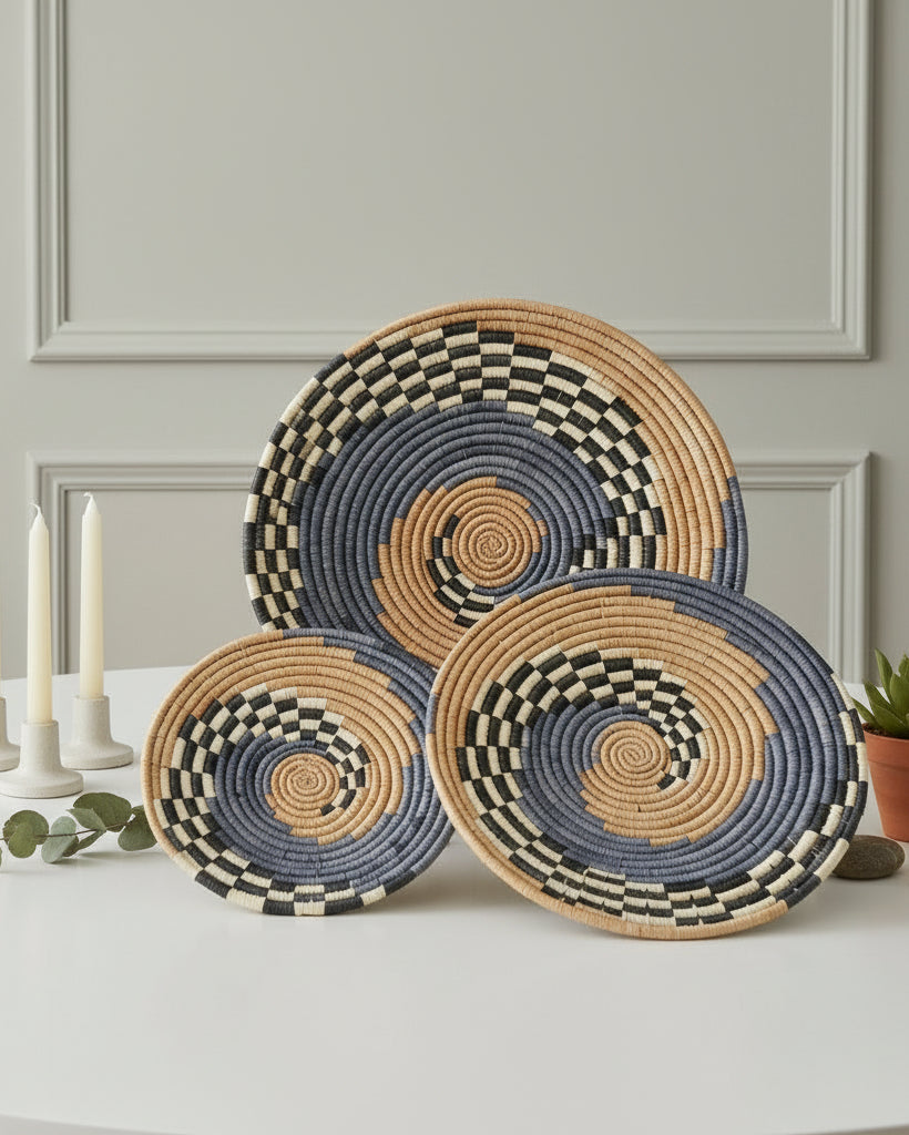 Dakarai Raffia Straw Wall Decor Display Basket Trays: Set of 3 handmade woven raffia palm fiber in a crochet loop technique creating a concentric swirl pattern of bands of cinnamon/tobacco/brown, grey, and black and natural straw color checked pattern in a three tone spiral from the center to the outer edge set of three sized flat bowl trays - Shebobo