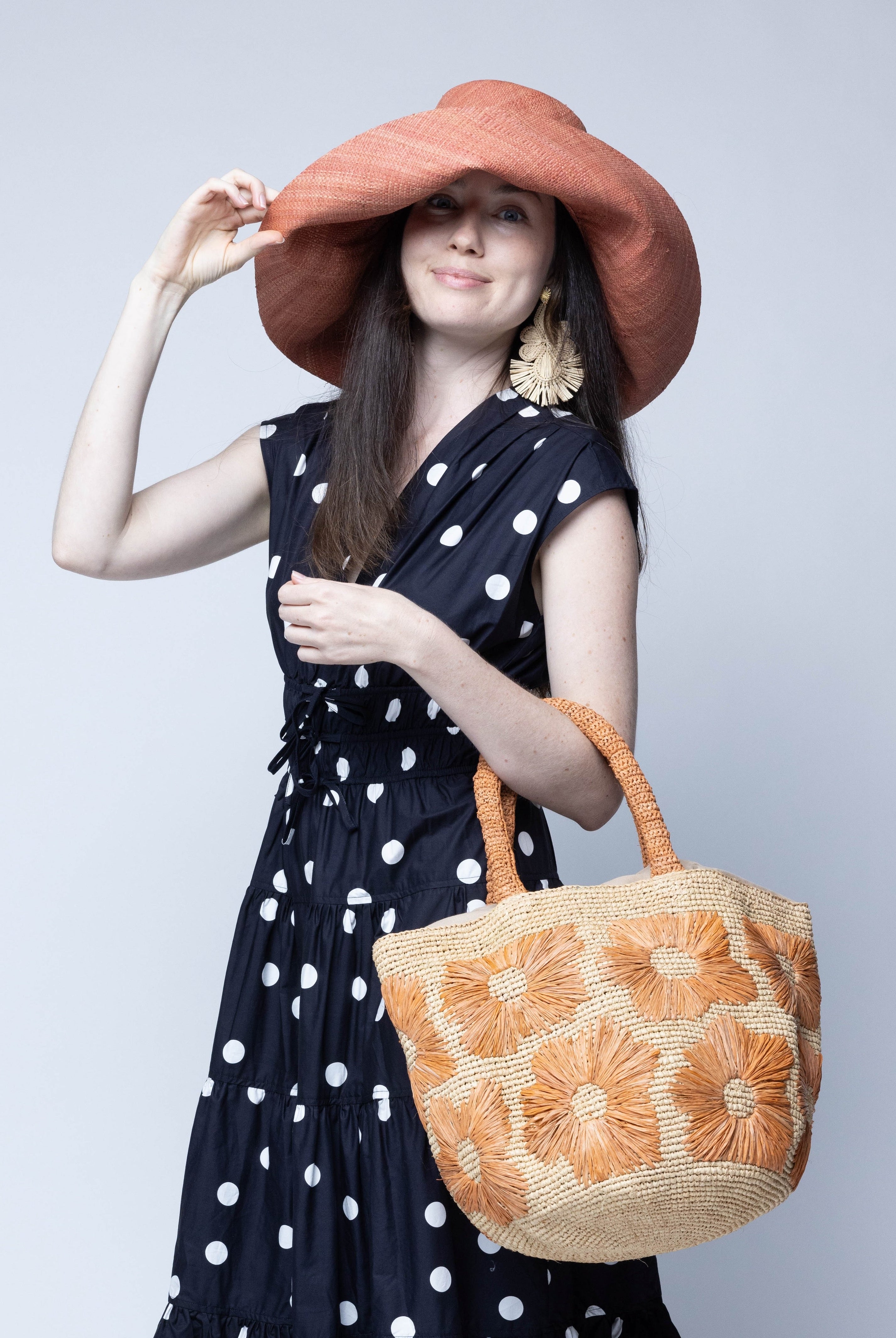 Model wearing Eva Embroidered Flower Crochet Straw Basket Handbag two tone handmade crochet raffia palm in a solid hue of natural straw color with blush pink/orange embroidered floral pattern and matching blush crochet handles beach bag tote purse - Shebobo (with Monica 5" & 7" Wide Brim Solid Color Packable Straw Sun Hats)