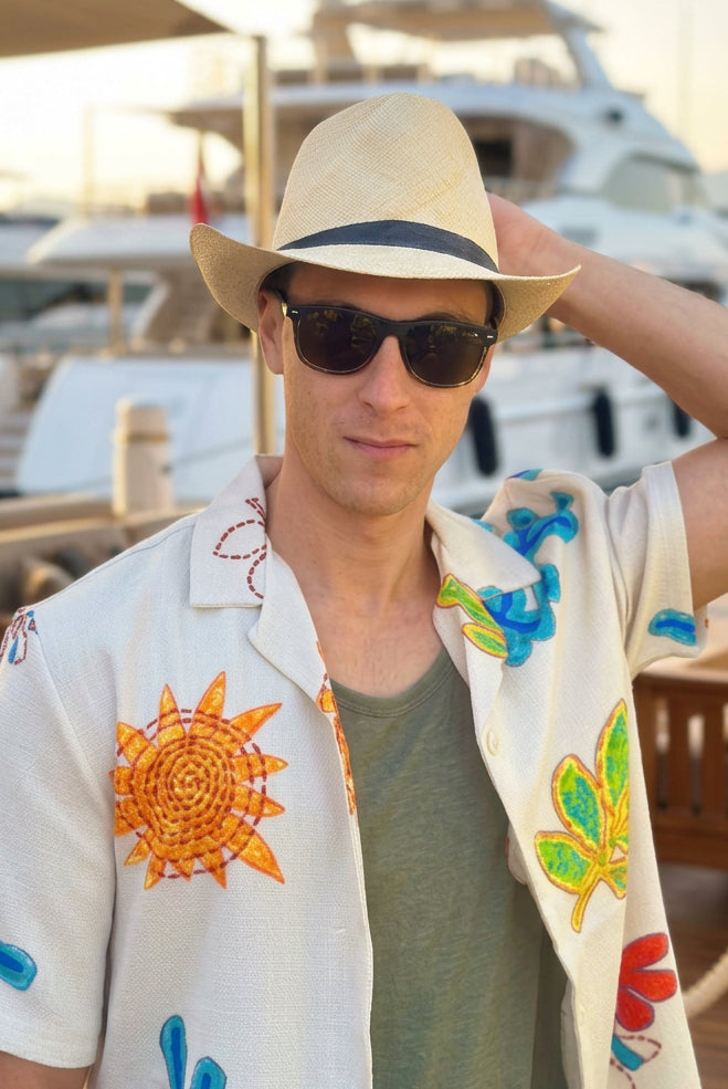 Model wearing Fedra Natural with Black Hat Band - Unisex Fedora Straw Hat handmade loomed natural raffia palm fiber in a solid hue of natural straw color with an attached black hat band - Shebobo