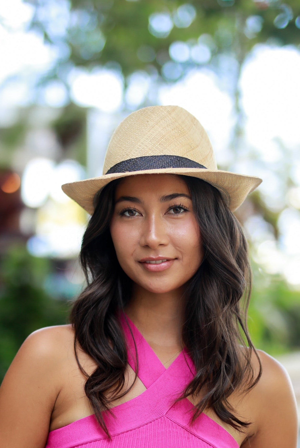 Model wearing Fedra Natural with Black Hat Band - Unisex Fedora Straw Hat handmade loomed natural raffia palm fiber in a solid hue of natural straw color with an attached black hat band - Shebobo