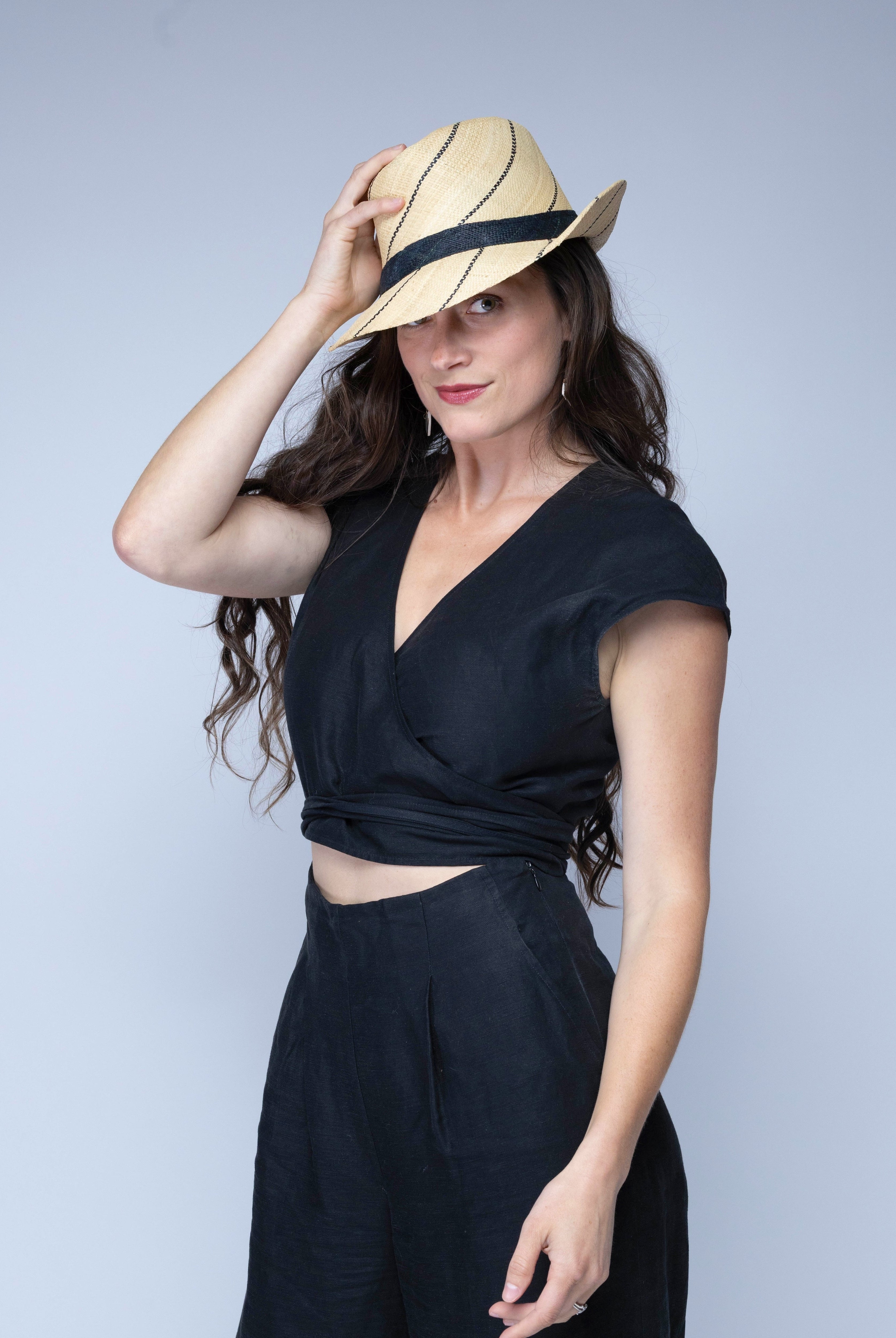 Model wearing Model wearing Fedra 2" Brim Fedora Unisex Straw Hats natural and black pinstripes packable raffia straw hat handmade loomed raffia in wide bands of natural straw color with black narrow bands create a stripe swirl pattern - Shebobo