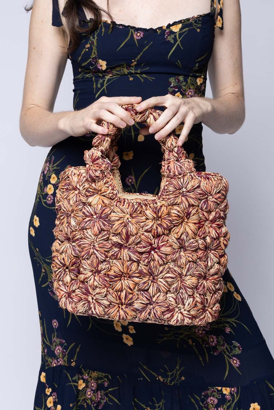Model wearing Florence Umberwine Burgundy Reds Multicolor Flower Crochet Straw Basket Handbag handmade natural raffia palm fiber in a multicolor hue combination of natural straw color, umberwine burgundy/claret/bordeaux/dark/red/purple, and blush orange/pink with subtle tied flower design consisting of 88 flowers crochet together along the outside of the bag as well as the handles purse tote - Shebobo