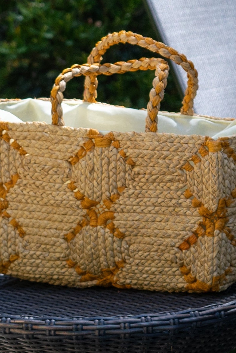 Lifestyle view Gemma Crochet Disc Rectangle Butter and Saffron Straw Basket Handbag handmade woven raffia palm fiber in a two tone multicolor pattern of butter light yellow and saffron yellow/orange create a coiled braid disc pattern result in a star pattern around the bag with matching woven handles top handle bag - Shebobo
