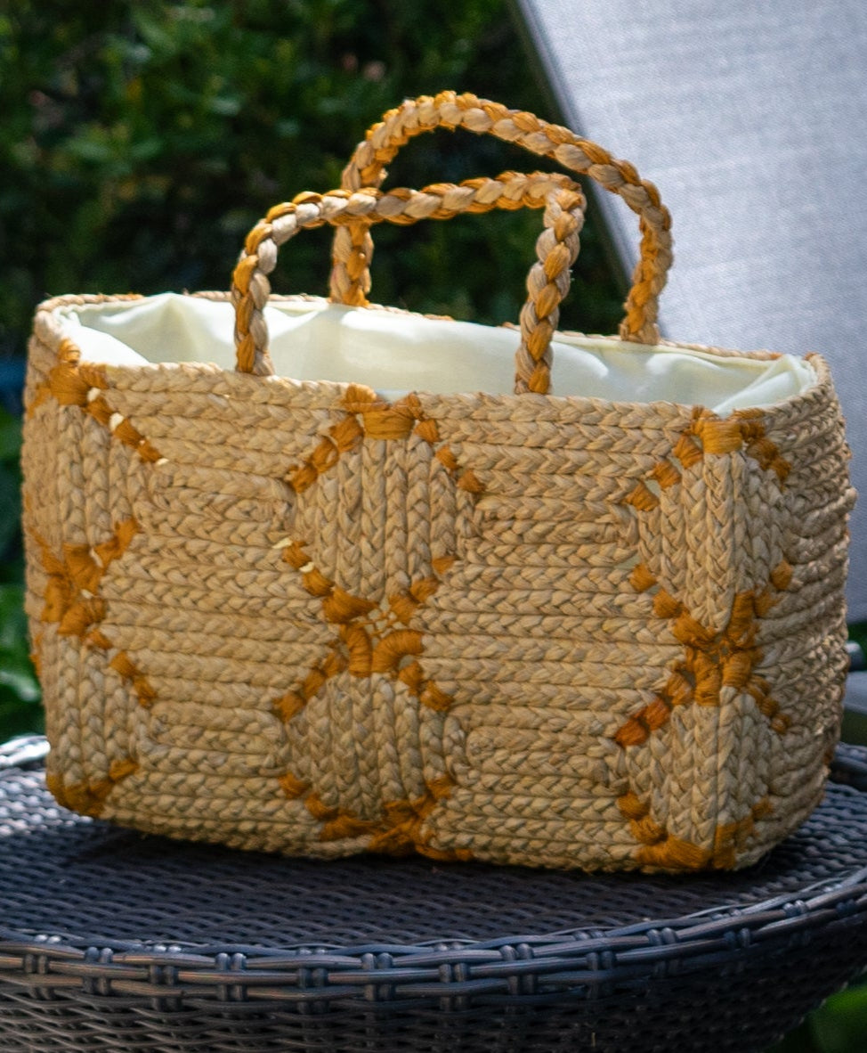 Lifestyle view Gemma Crochet Disc Rectangle Butter and Saffron Straw Basket Handbag handmade woven raffia palm fiber in a two tone multicolor pattern of butter light yellow and saffron yellow/orange create a coiled braid disc pattern result in a star pattern around the bag with matching woven handles top handle bag - Shebobo