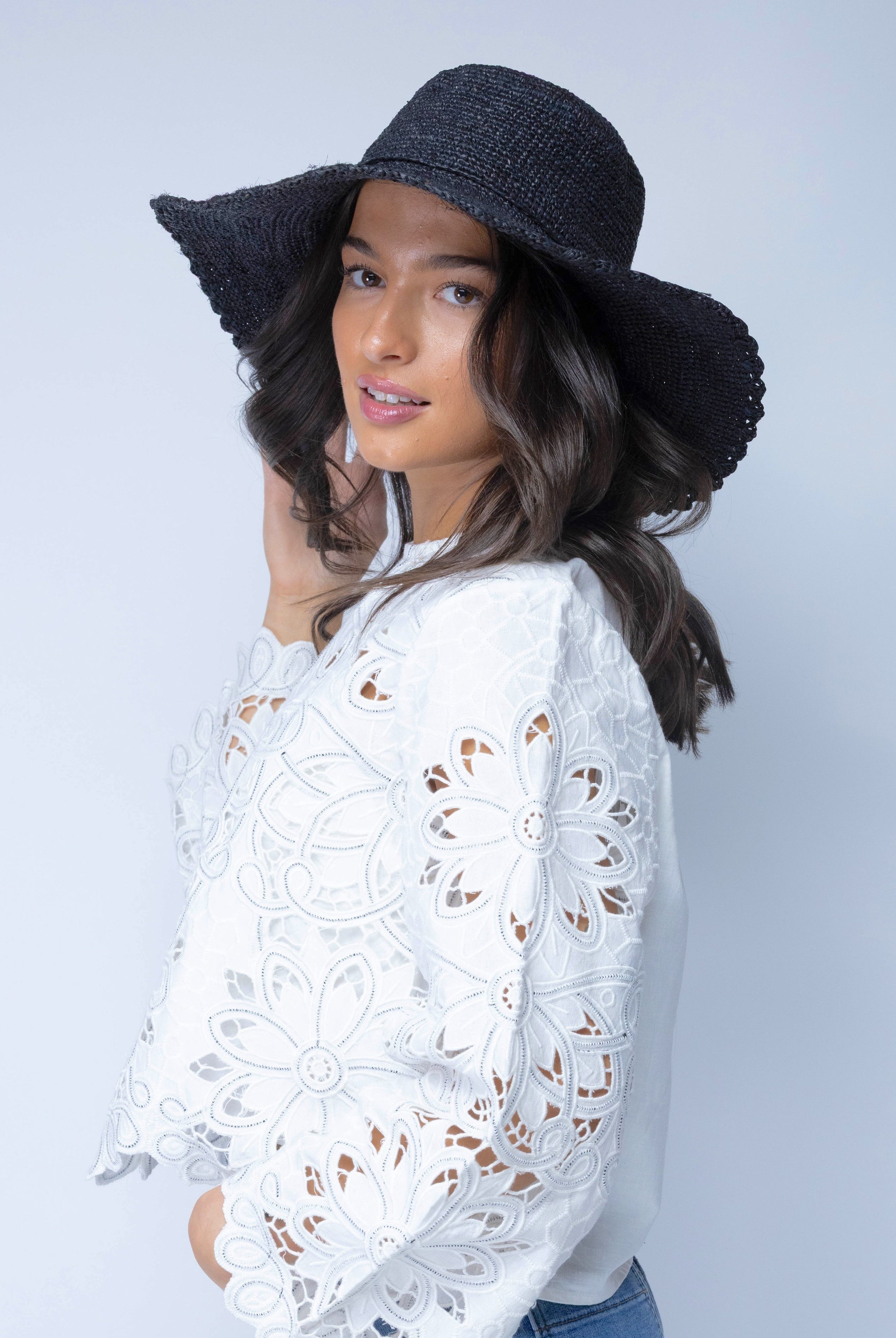 Model wearing 4" Brim Genevieve Black Crochet Straw Sun Hat with Lace Weave Edge handmade raffia palm fiber crochet solid hue black rounded crown with detailed lace weave edge and matching adjustable hat band - Shebobo