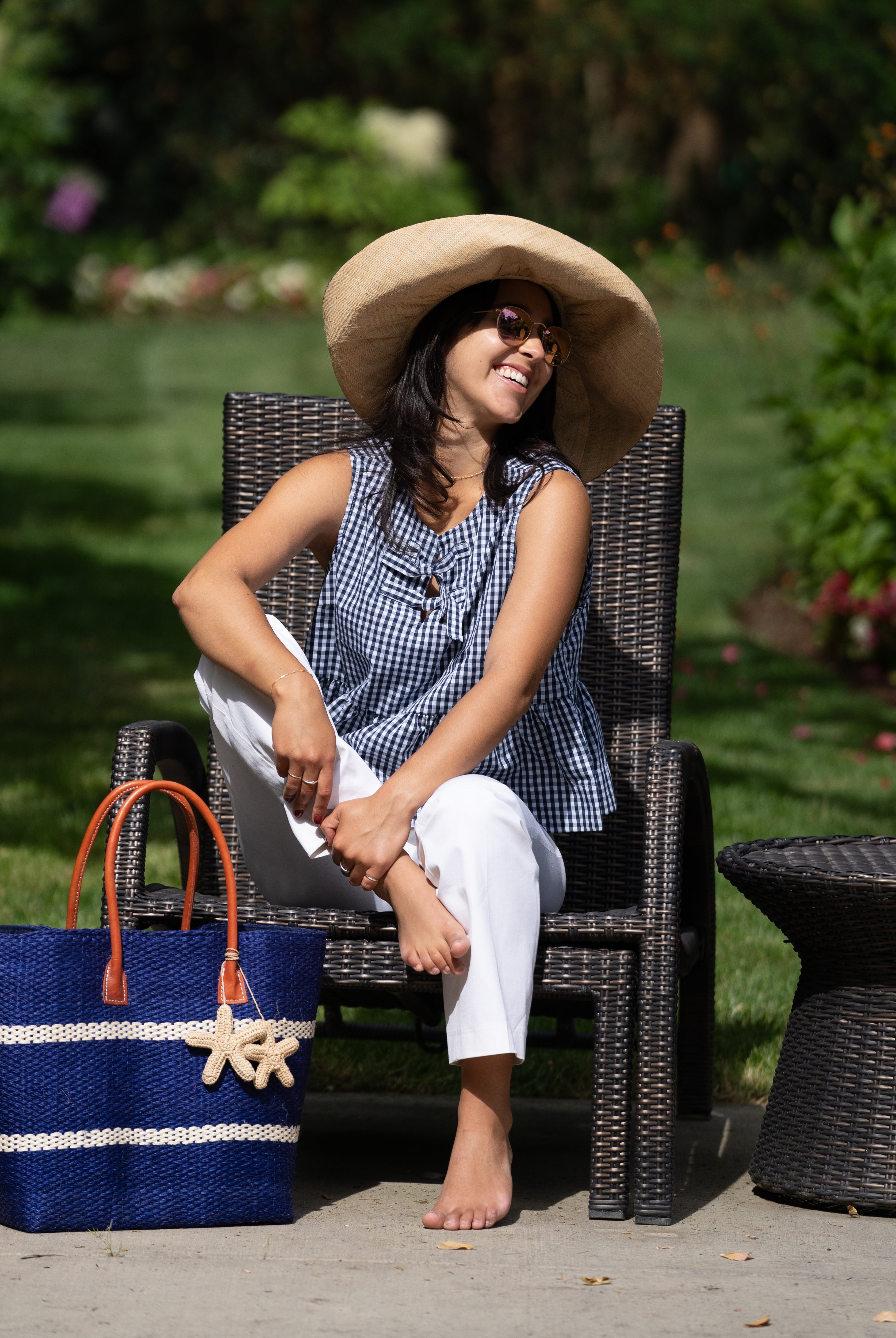 Model wearing Havana Sisal Basket Bag with Tassel Charm Embellishment handmade sisal fiber woven into horizontal wide bands of dusk dark blue with two evenly spaced narrow bands of natural straw color create a stripe pattern with natural crochet starfish charm embellishment and leather handles handbag shoulder bag - Shebobo (with 7" Wide Brim Packable Straw Sun Hat)