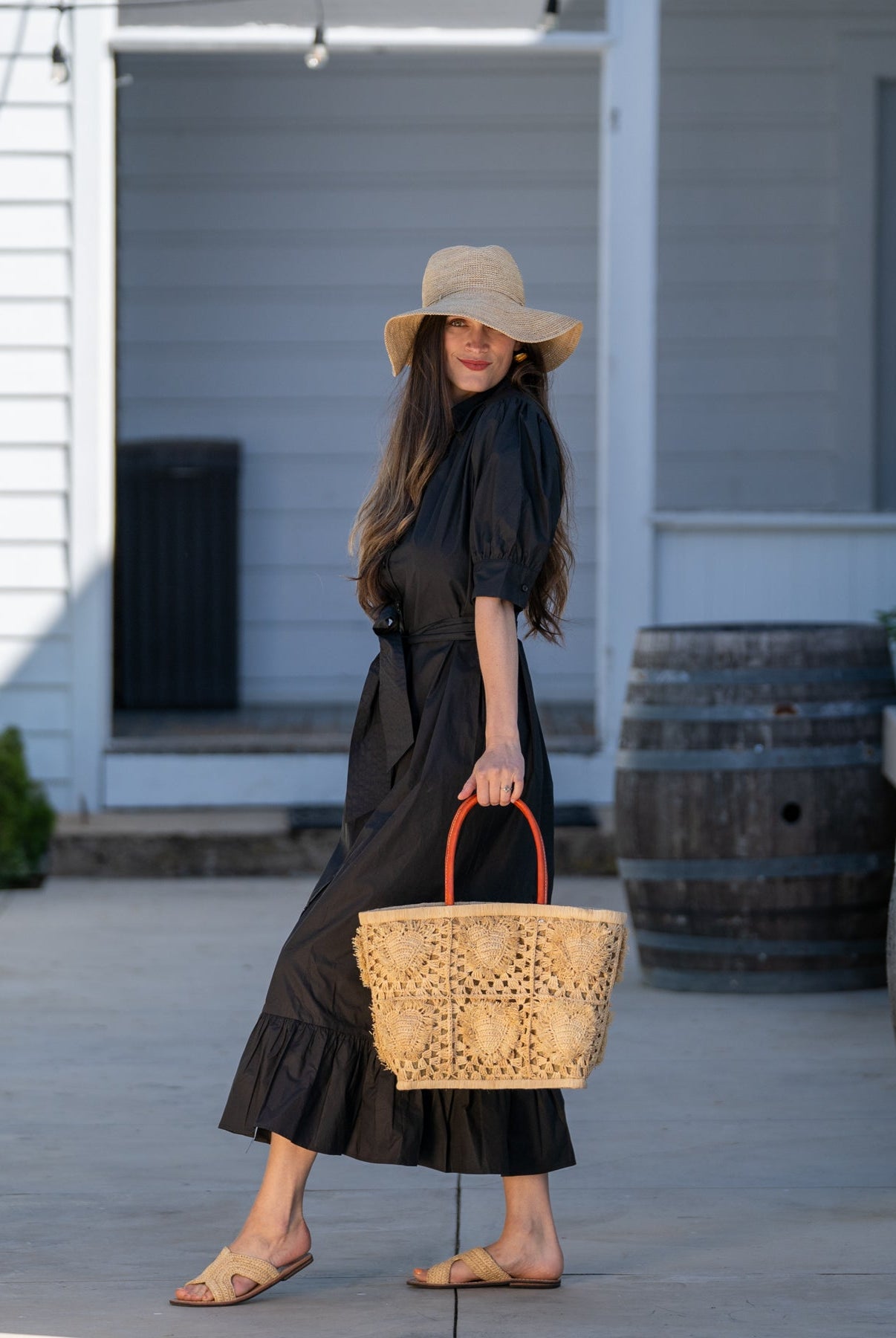 Model wearing Hearts Crochet Straw Basket Bag with Fringed Heart Pattern handmade woven raffia in a solid hue of natural straw color with granny square pattern and raised/stuffed heart pattern with fringe edges on each heart, looped base and top binding, as well as leather handles purse beach bag shoulder bag - Shebobo (with 3.5" Brim Crochet Miramar Straw Sun Hat and Lizzie Crochet Straw Sandals)