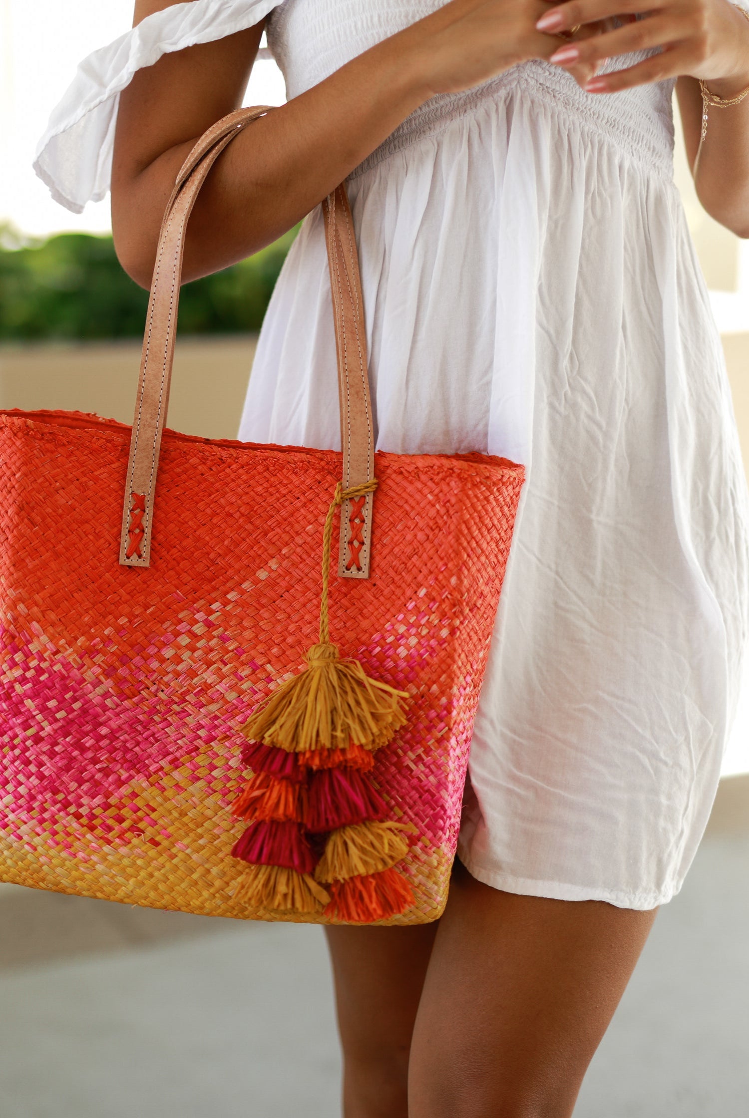 Model wearing Holden Ombre Fuchsia Straw Handbag Tassel Charm Embellishment handmade woven raffia dip dyed gradient of coral orange/red, fuchsia bright pink, and saffron yellow with matching multicolored, multi-tiered raffia tuft tassel - Shebobo