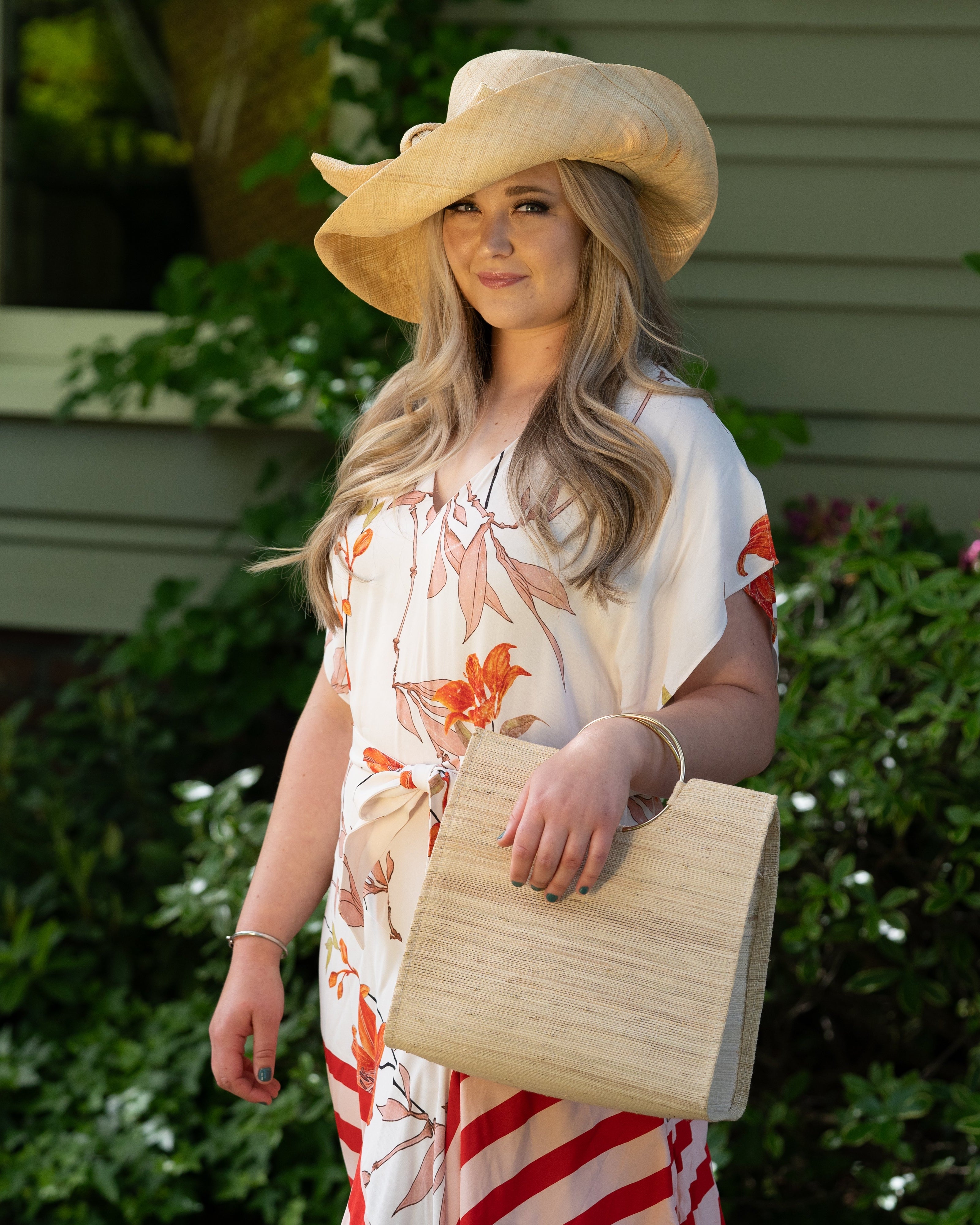 Model wearing JoJo Woven Straw Handbag with Metal Ring Handle handmade natural raffia palm fiber in a solid hue of natural straw color with matching woven thread texture and metallic circular metal ring handle - Shebobo (with Wide Brim Big Bow Solid Color Packable Straw Sun Hats)
