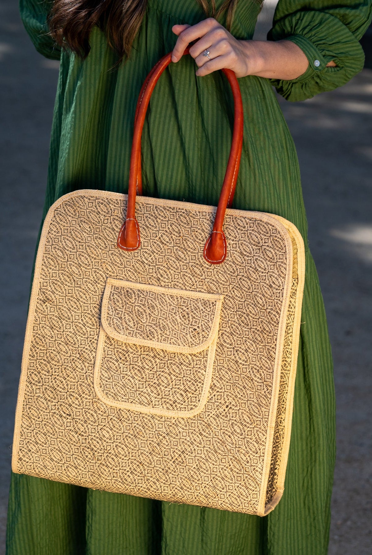 Model wearing Josephine 50's Inspired Woven Straw Handbag handmade natural raffia palm fiber in natural straw color woven with contrasting Black thread stitching in a subtle diagonal stripe pattern consisting of bands of ovals and circles with loomed raffia edging around the bag as well as the pocket and flap of the exterior pocket - Shebobo