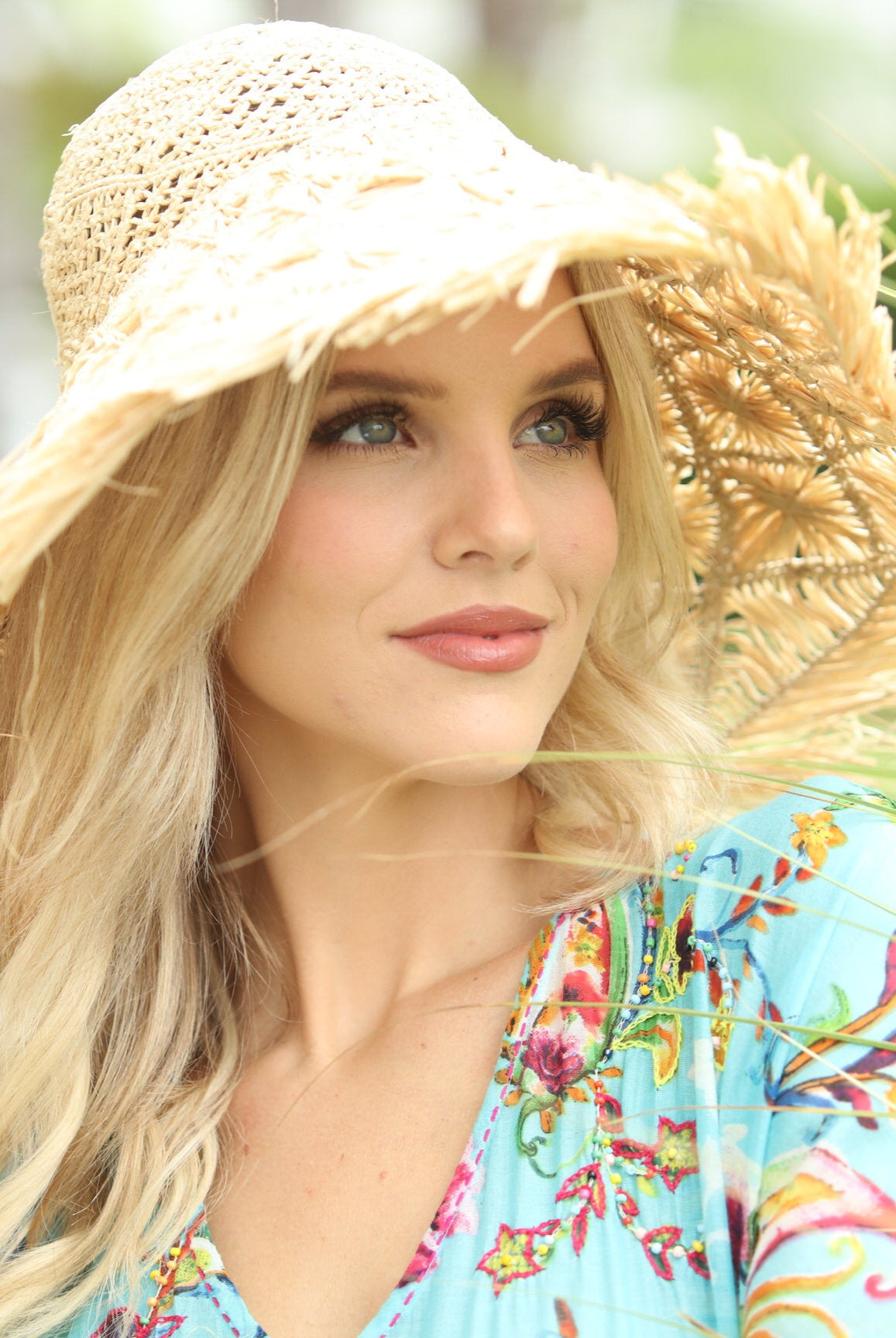 Model wearing Karin Crochet & Macrame Natural Raffia Knotted Straw Sun Hat Lightweight Breathable with Fringe Edge geometric star or sunburst design brim and geometric diamond pattern top - Shebobo