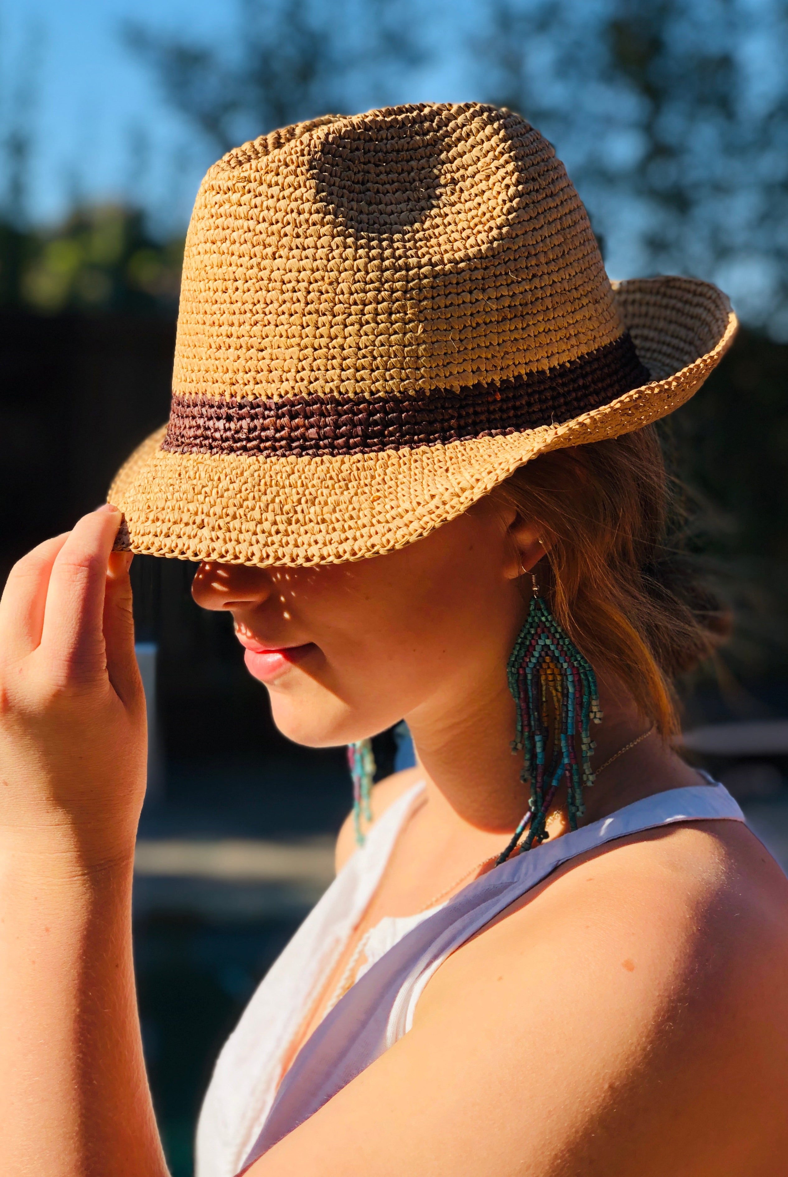 Model wearing Kelly Crochet Fedora - Unisex Straw Sun Hats handmade woven natural raffia palm fiber in a solid hue of natural straw color with woven in hatband of cinnamon/tobacco/brown - Shebobo