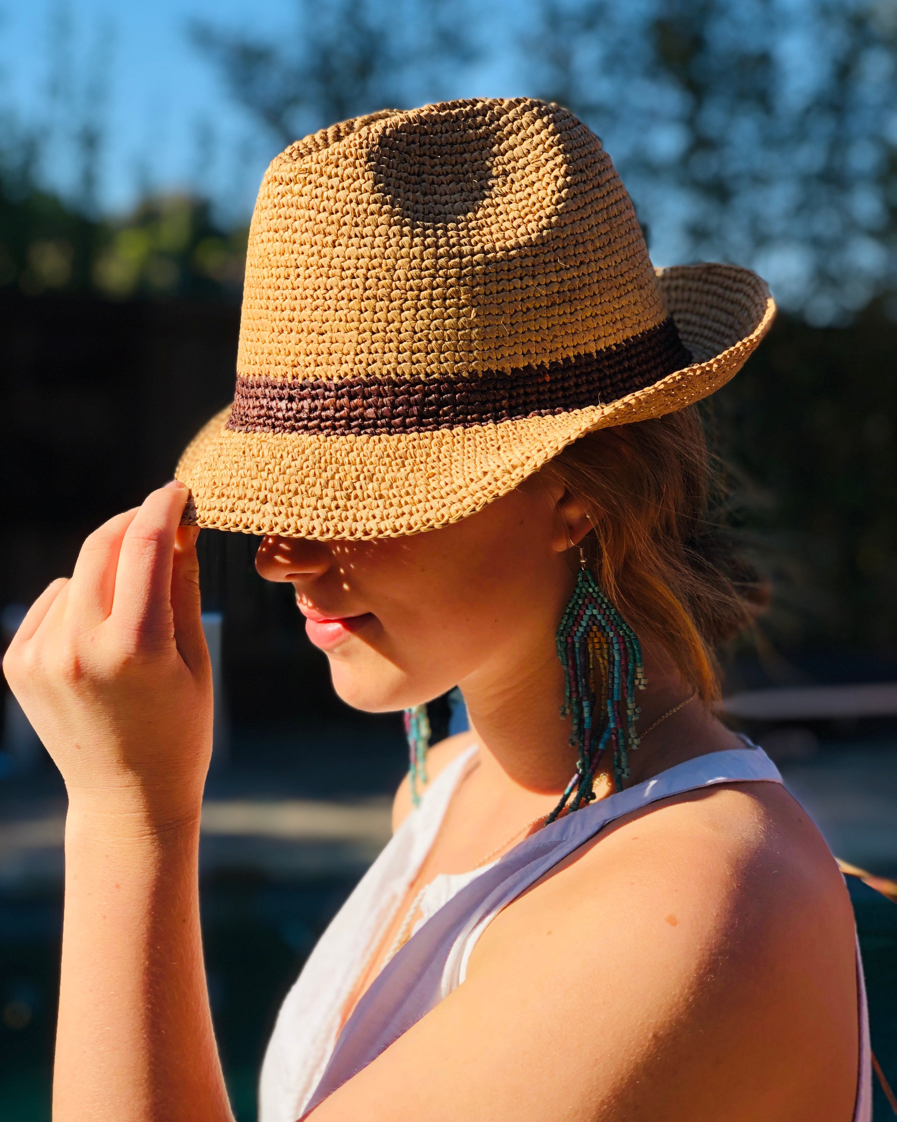 Model wearing Kelly Crochet Fedora - Unisex Straw Sun Hats handmade woven natural raffia palm fiber in a solid hue of natural straw color with woven in hatband of cinnamon/tobacco/brown - Shebobo
