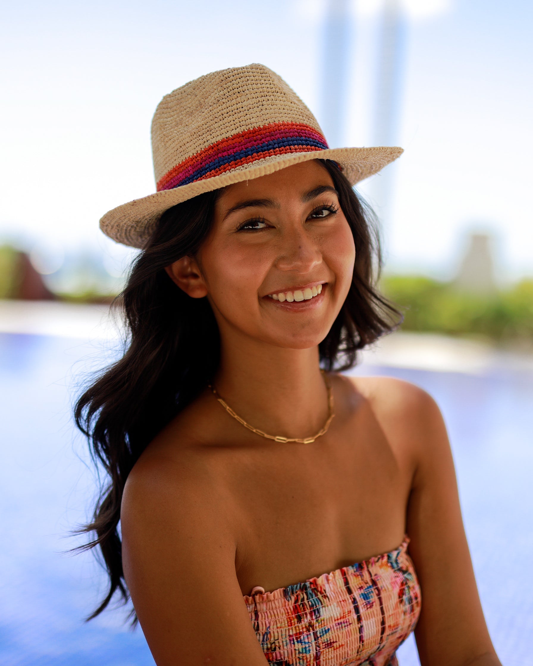 Model wearing Kelly Crochet Fedora - Unisex Straw Sun Hats handmade woven natural raffia palm fiber in a solid hue of natural straw color with woven in multicolored hatband of fuchsia bright/hot/barbie/pink, coral orange/red, and navy blue hues - Shebobo