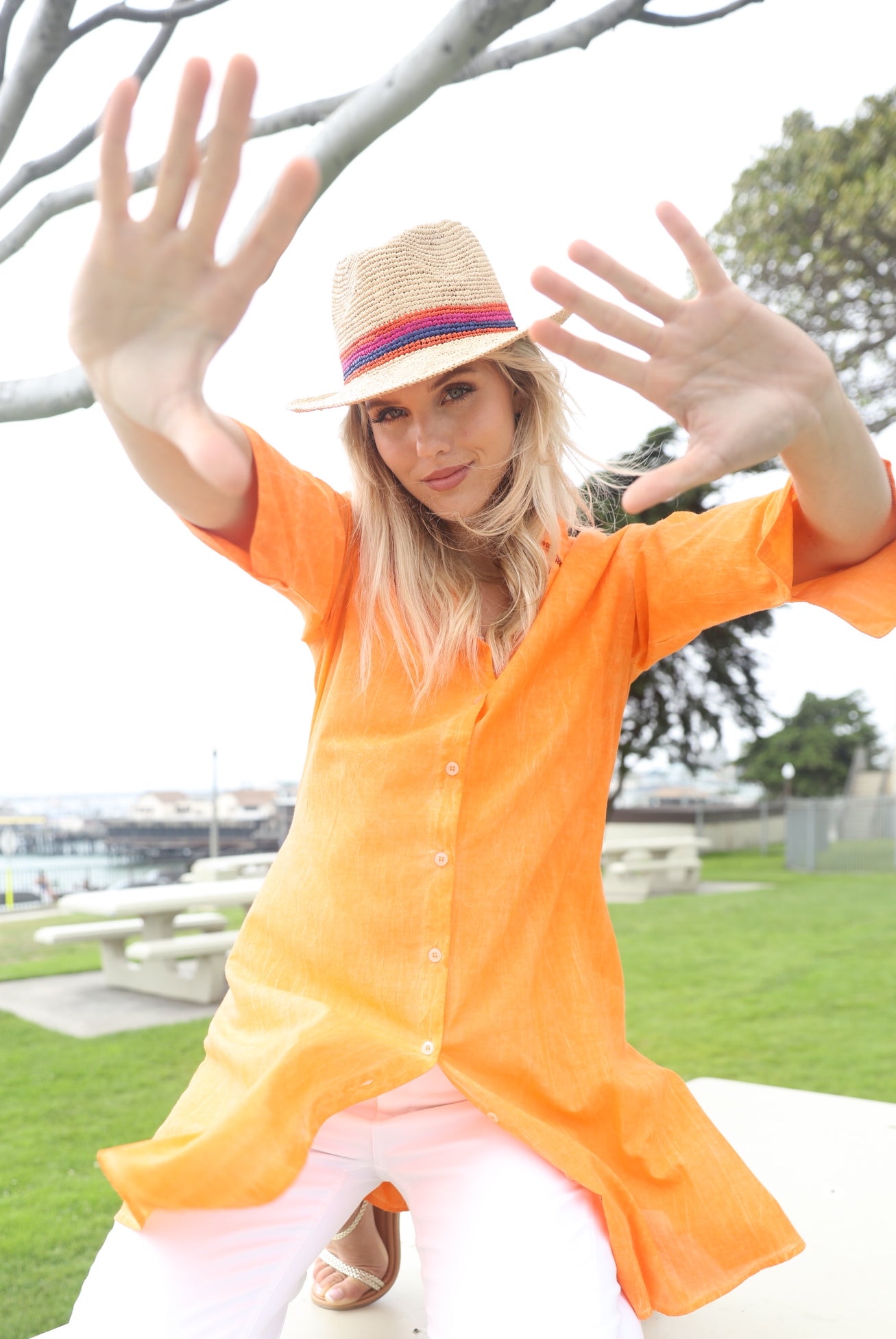 Model wearing Kelly Crochet Fedora - Unisex Straw Sun Hats handmade woven natural raffia palm fiber in a solid hue of natural straw color with woven in multicolored hatband of fuchsia bright/hot/barbie/pink, coral orange/red, and navy blue hues - Shebobo