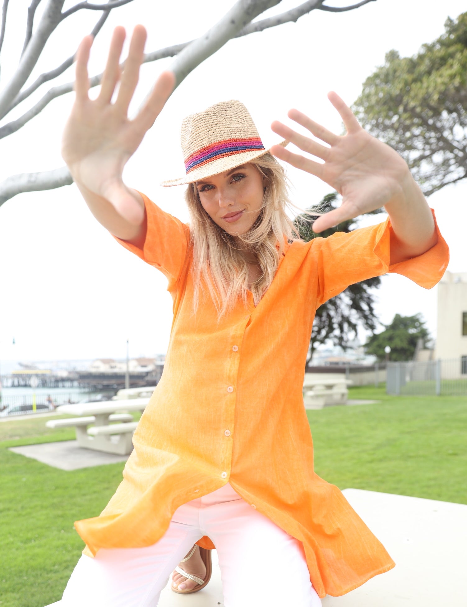 Model wearing Kelly Crochet Fedora - Unisex Straw Sun Hats handmade woven natural raffia palm fiber in a solid hue of natural straw color with woven in multicolored hatband of fuchsia bright/hot/barbie/pink, coral orange/red, and navy blue hues - Shebobo