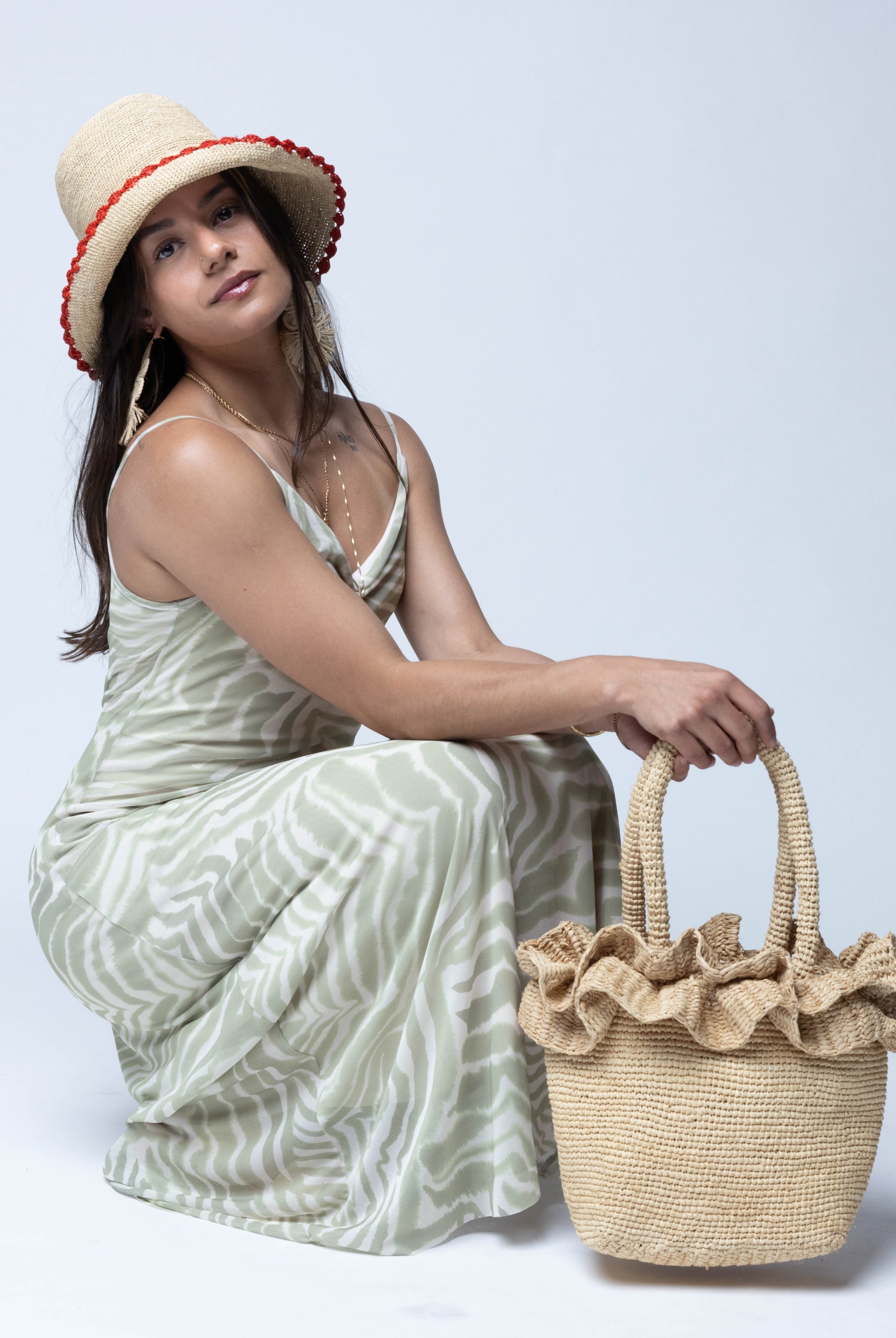 Model wearing Kiri Ruffle Crochet Straw Basket Handbag handmade crochet natural raffia palm fiber in a solid hue of natural straw color in subtle link texture with sweet double ruffle embellishment around the top of the bag and matching crochet handles beach bag shoulder bag - Shebobo (with Kate 3" Brim Crochet Bucket Straw Hats with Colored Lace Weave Edge)