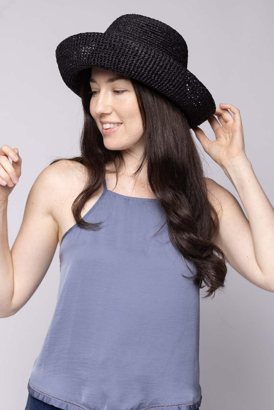 Model wearing Leor Black crochet straw hat handmade woven natural raffia palm fiber in a solid hue of black raffia 3" brim packable straw hat with matching adjustable braided hat band - Shebobo