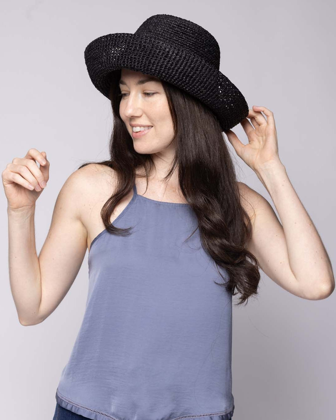 Model wearing Leor Black crochet straw hat handmade woven natural raffia palm fiber in a solid hue of black raffia 3" brim packable straw hat with matching adjustable braided hat band - Shebobo