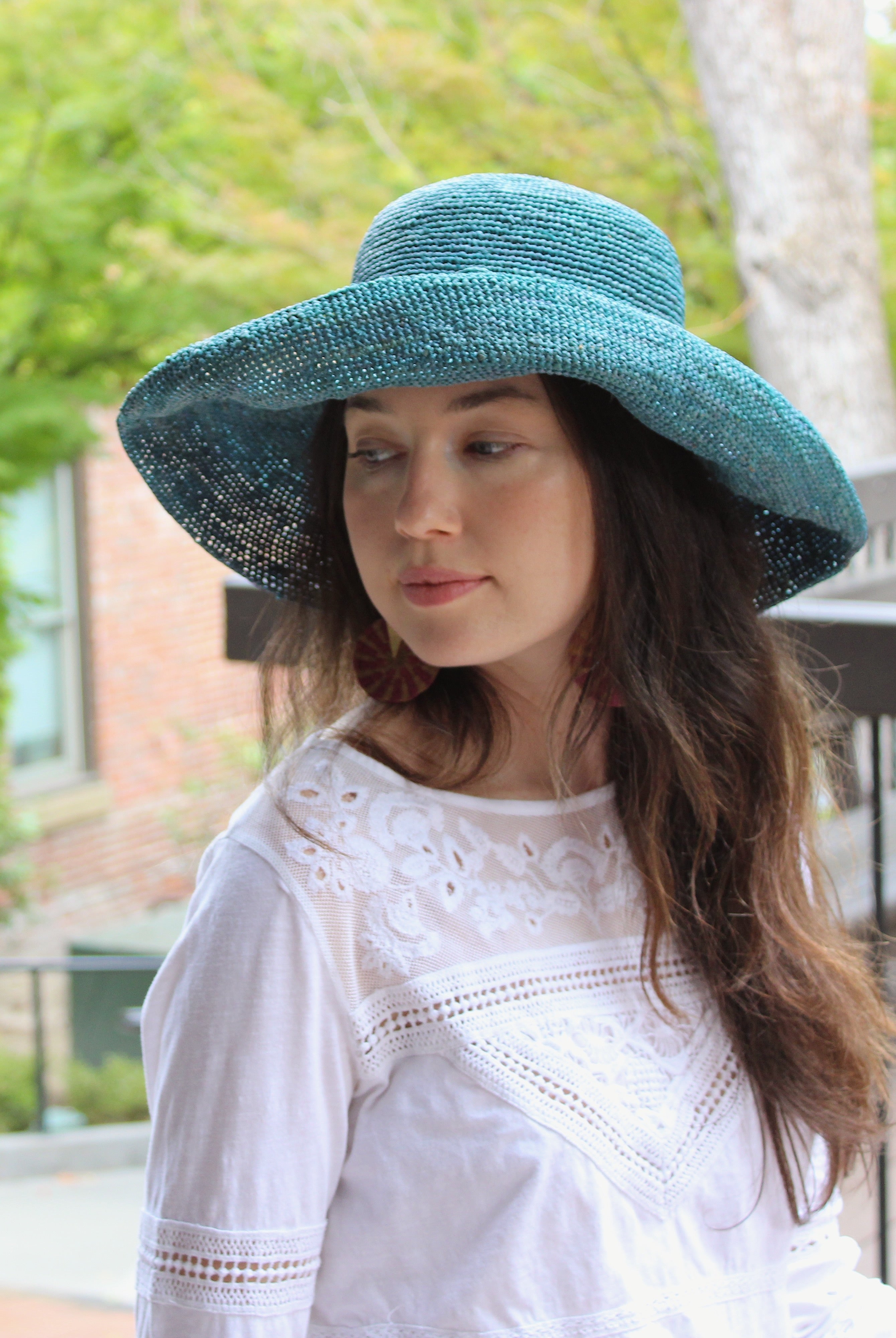 Model wearing Leor Turquoise crochet straw hat handmade woven natural raffia palm fiber in a solid hue of turquoise blue/green raffia 3" brim packable straw hat with matching adjustable braided hat band - Shebobo