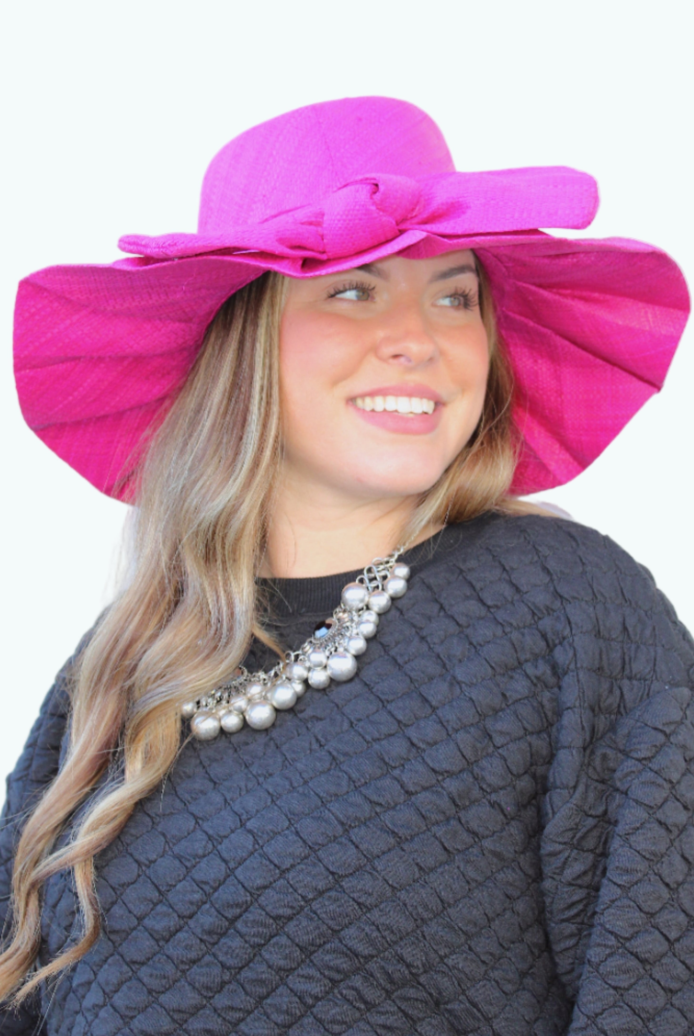 Model wearing Lilly 5" Brim Fan Straw Sun Hat with Big Bow Fuchsia handmade loomed natural raffia palm fiber in a solid hue of Fuchsia hot/bright/barbie/pink with pleated wide brim and oversized bow embellishment - Shebobo