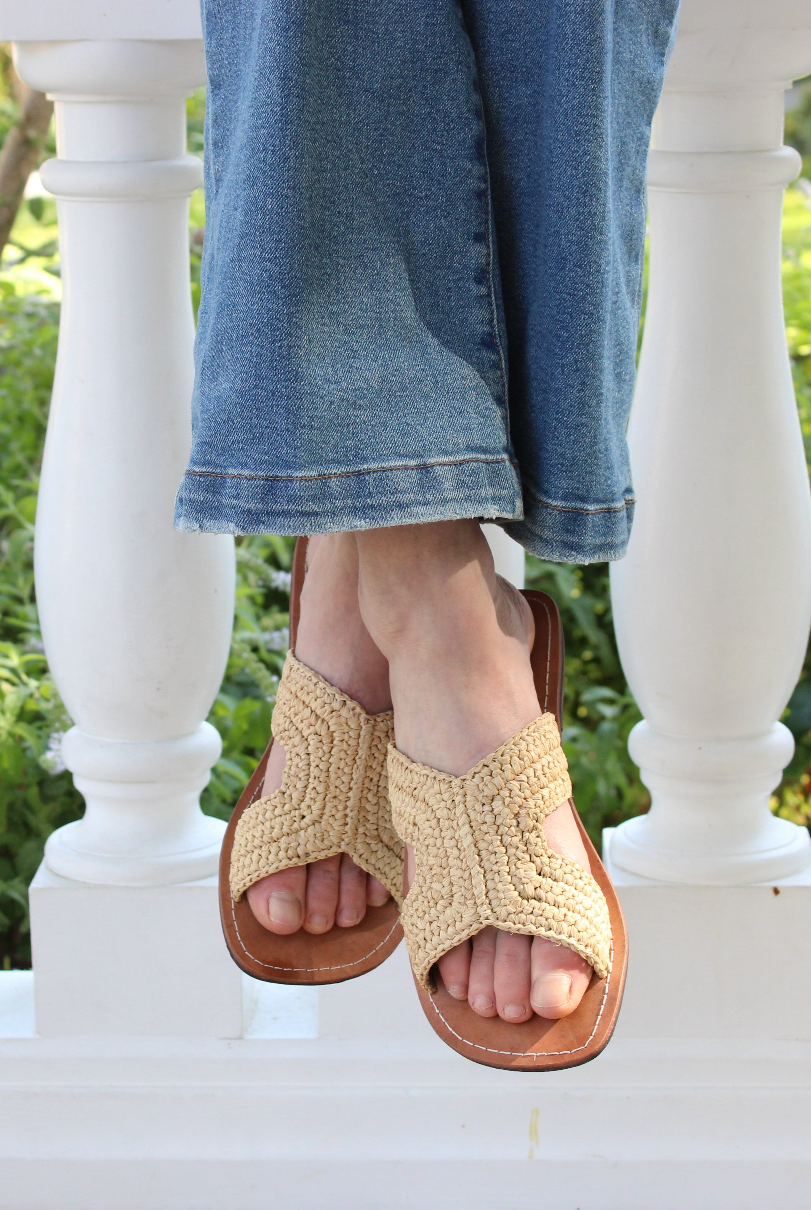 Model wearing Lizzie Crochet Straw & Leather Sandal handmade crochet natural raffia palm fiber in a solid hue of natural straw color in a h-shape double band across the top of the shoe and leather soles summer slide shoe - Shebobo