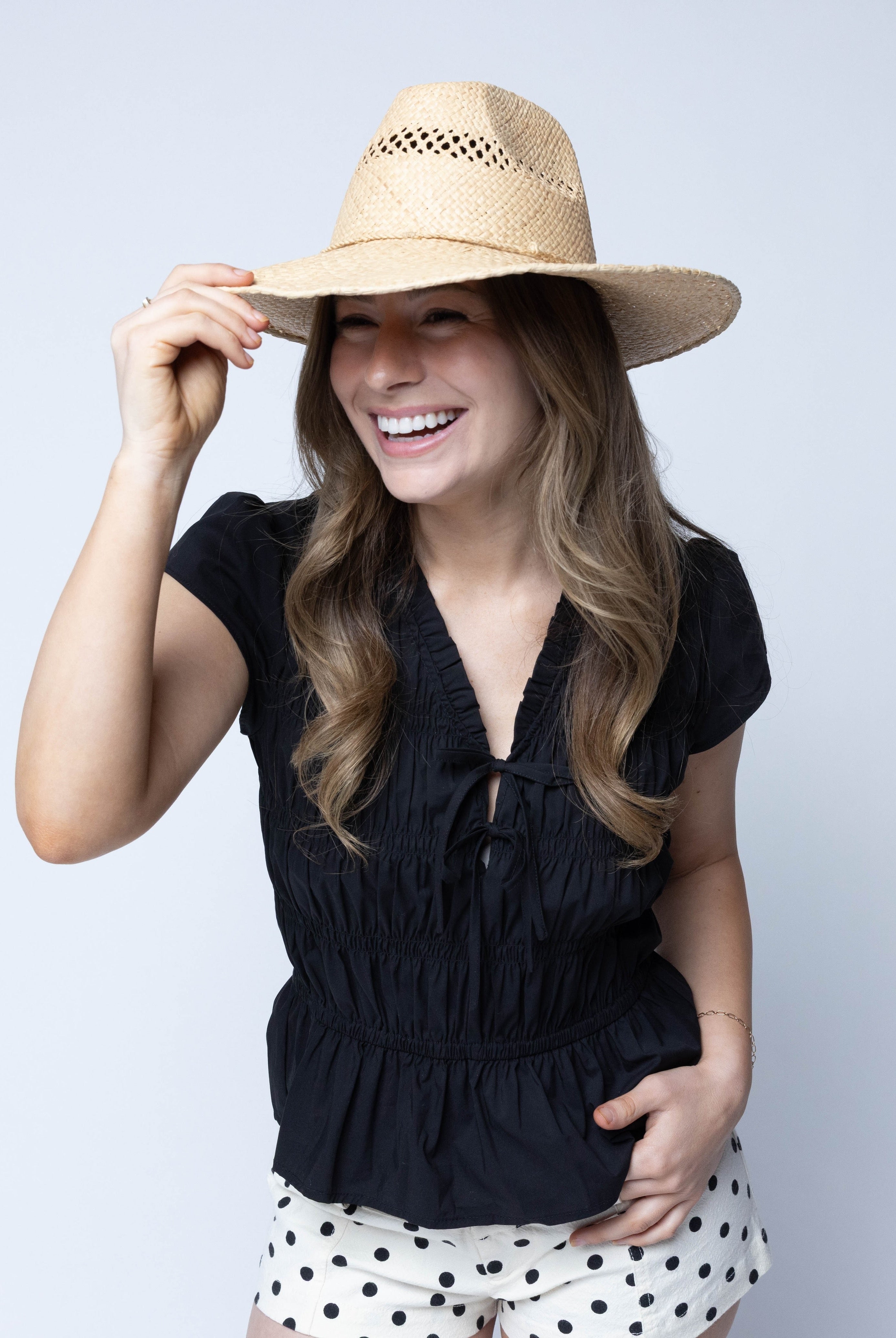 Model wearing Macho Natural Unisex Straw Cowboy Hat with Adjustable Wire Rim handmade woven raffia in a solid hue of natural straw color in a structured crown style with open weave pattern for breathability and pliable wire rim with matching twisted cord hat band - Shebobo