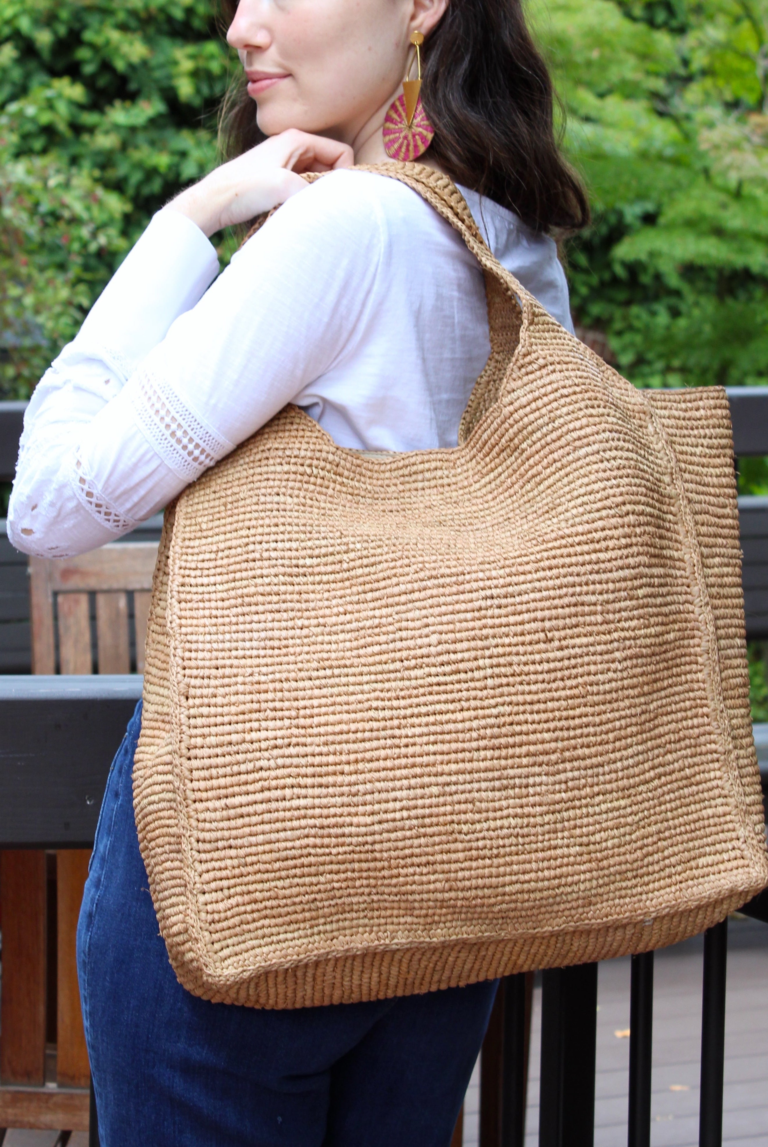 Model wearing Mamie XL Crochet Straw Basket Handbag handmade crochet natural raffia palm fiber in a solid hue of cappuccino tea/light/brown purse beach bag - Shebobo