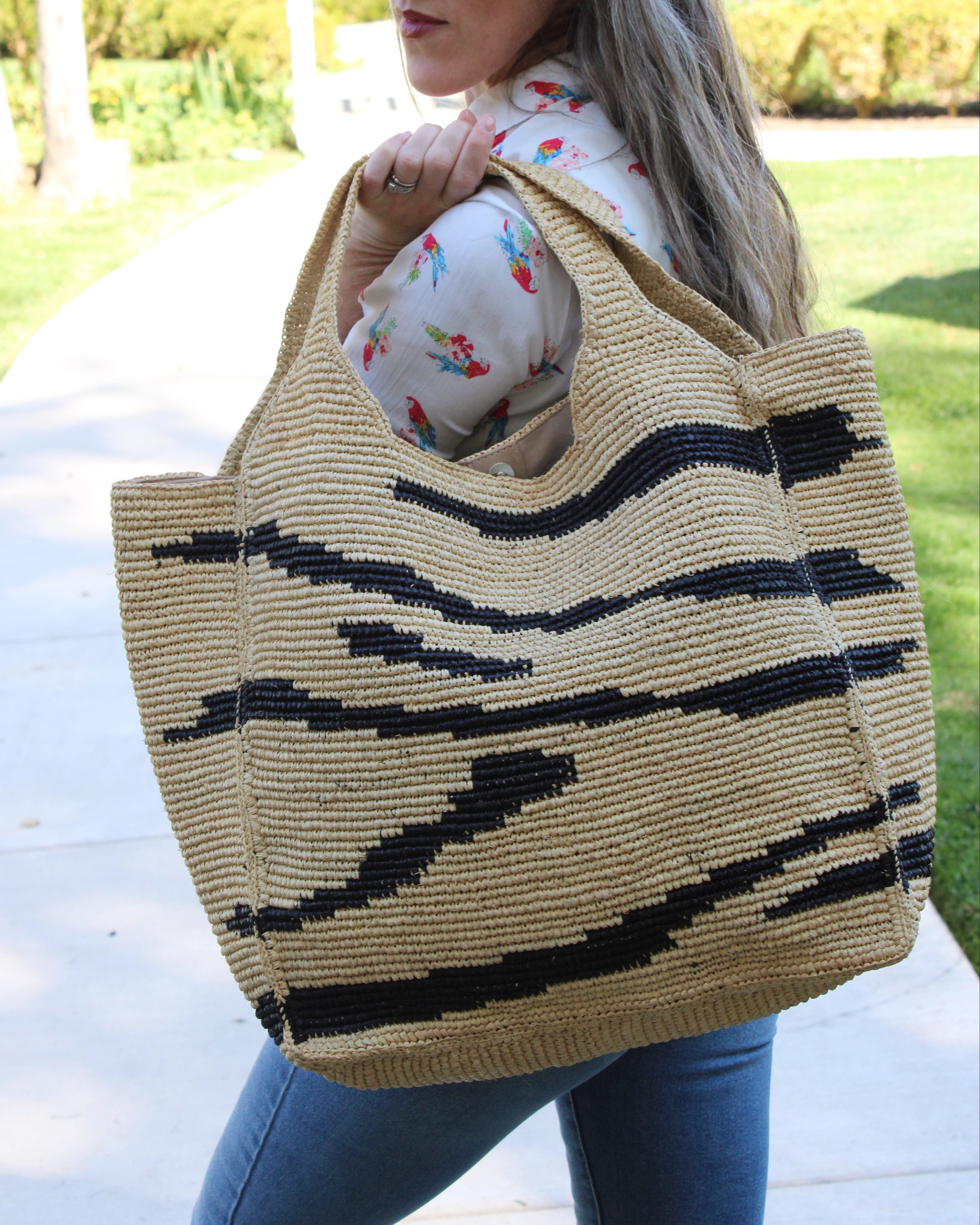 Model wearing Mamie XL Crochet Straw Basket Handbag handmade crochet natural raffia palm fiber in a two tone natural and black zebra stripe pattern purse beach bag - Shebobo