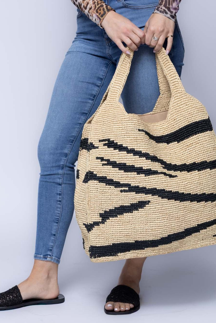 Model wearing Mamie XL Crochet Straw Basket Handbag handmade crochet natural raffia palm fiber in a two tone natural and black zebra stripe pattern purse beach bag - Shebobo