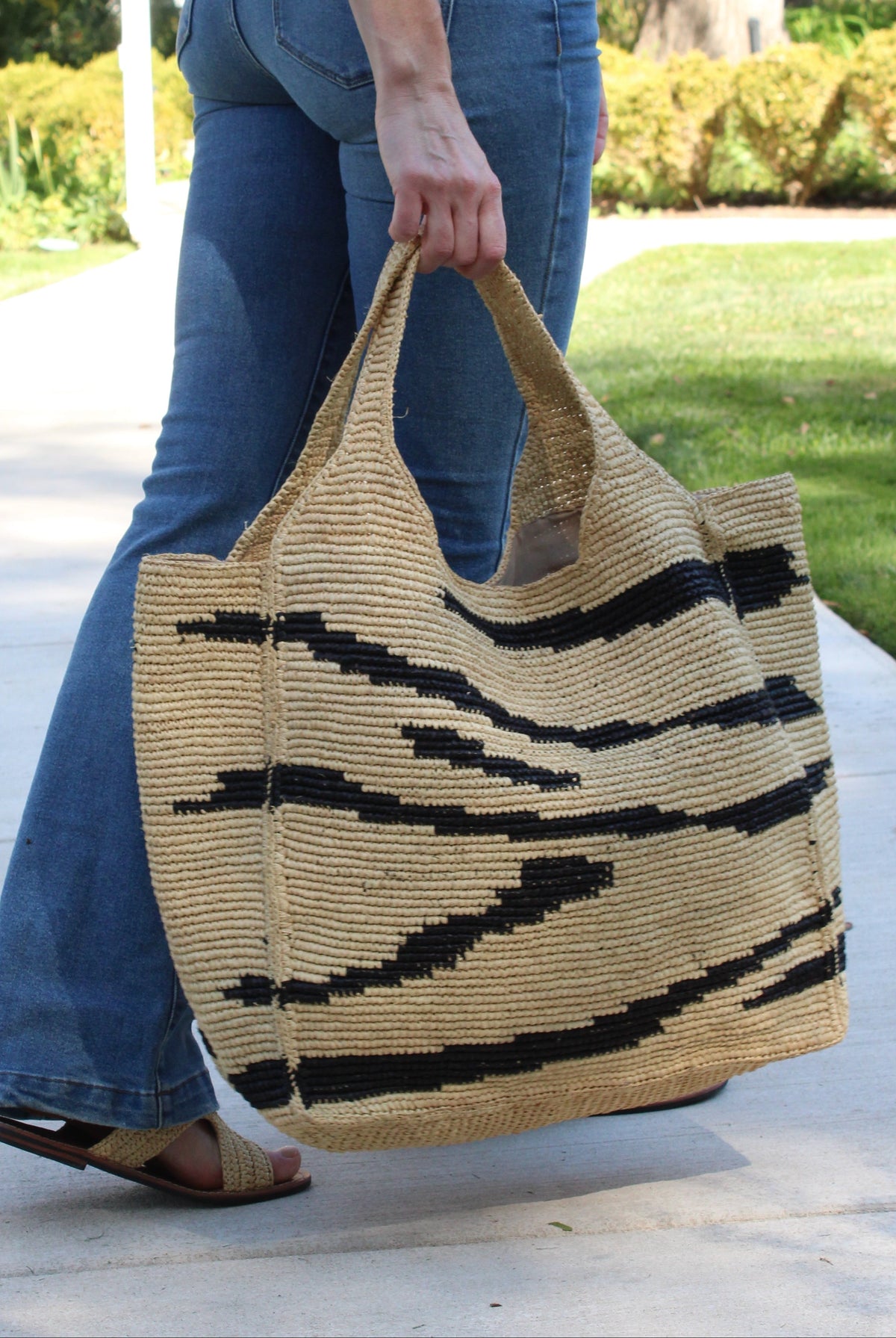Model wearing Mamie XL Crochet Straw Basket Handbag handmade crochet natural raffia palm fiber in a two tone natural and black zebra stripe pattern purse beach bag - Shebobo