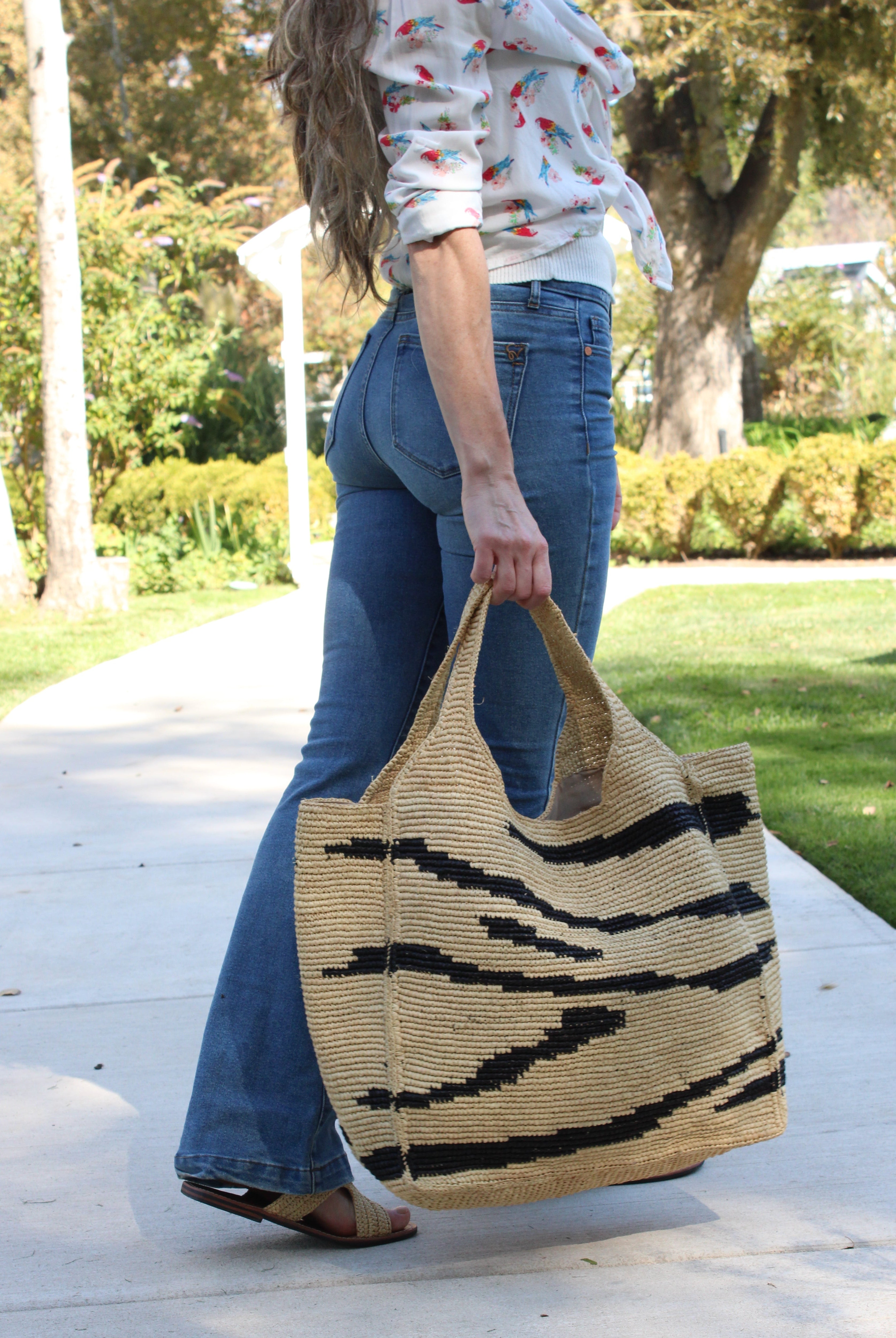 Model wearing Mamie XL Crochet Straw Basket Handbag handmade crochet natural raffia palm fiber in a two tone natural and black zebra stripe pattern purse beach bag - Shebobo