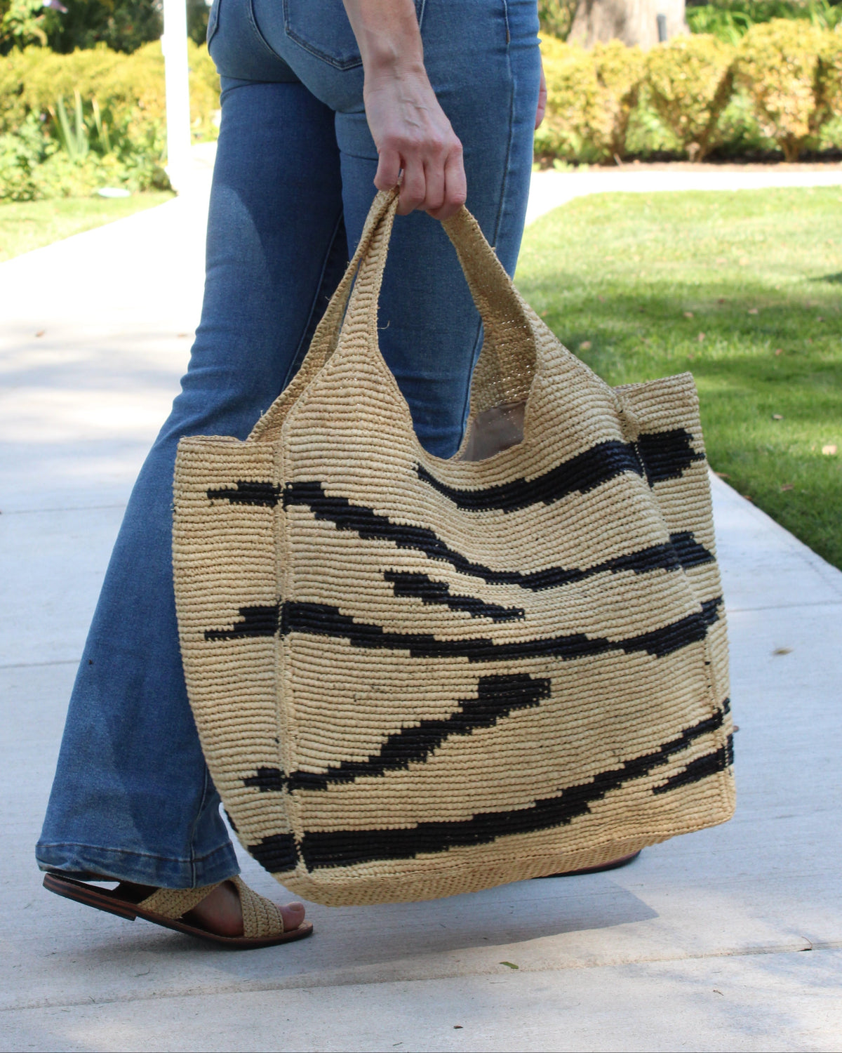 Model wearing Mamie XL Crochet Straw Basket Handbag handmade crochet natural raffia palm fiber in a two tone natural and black zebra stripe pattern purse beach bag - Shebobo