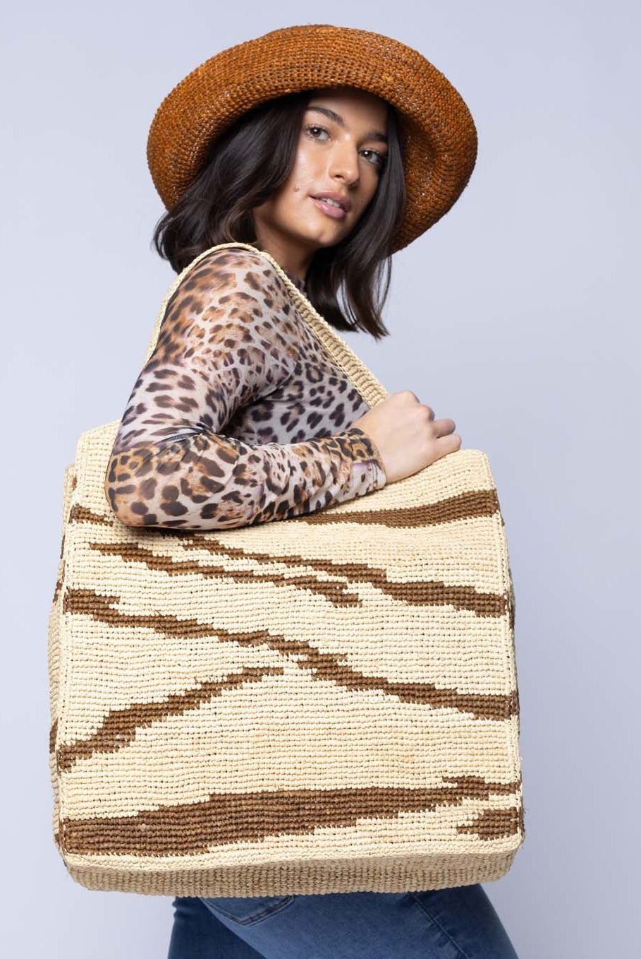 Model wearing Side view Mamie XL Crochet Straw Basket Handbag handmade crochet natural raffia palm fiber in a two tone natural straw color and tobacco dark/cinnamon/brown zebra stripe pattern purse beach bag - Shebobo
