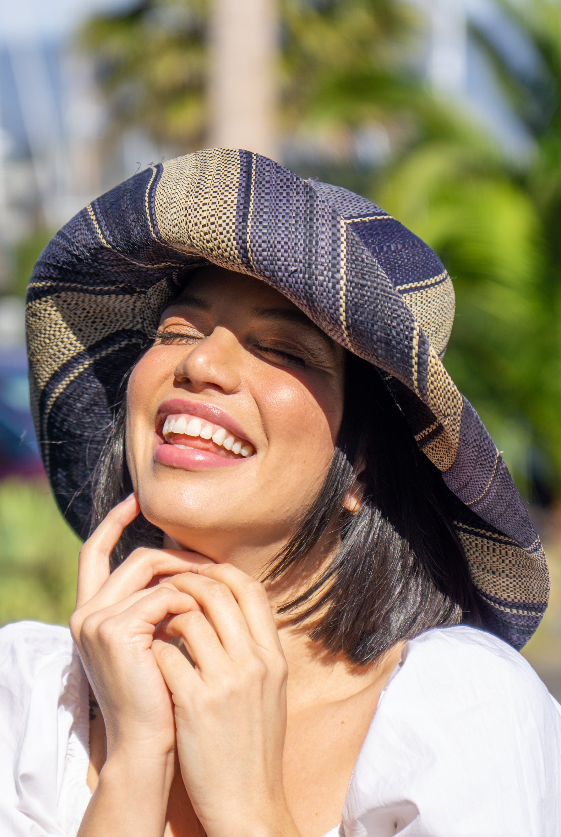 Model wearing Monica 5" Wide Brim Black Swirl Multicolor Stripe Pattern Packable Straw Sun Hat handmade loomed raffia in multi width bands of black, grey, and natural straw color create a striped swirl pattern - Shebobo