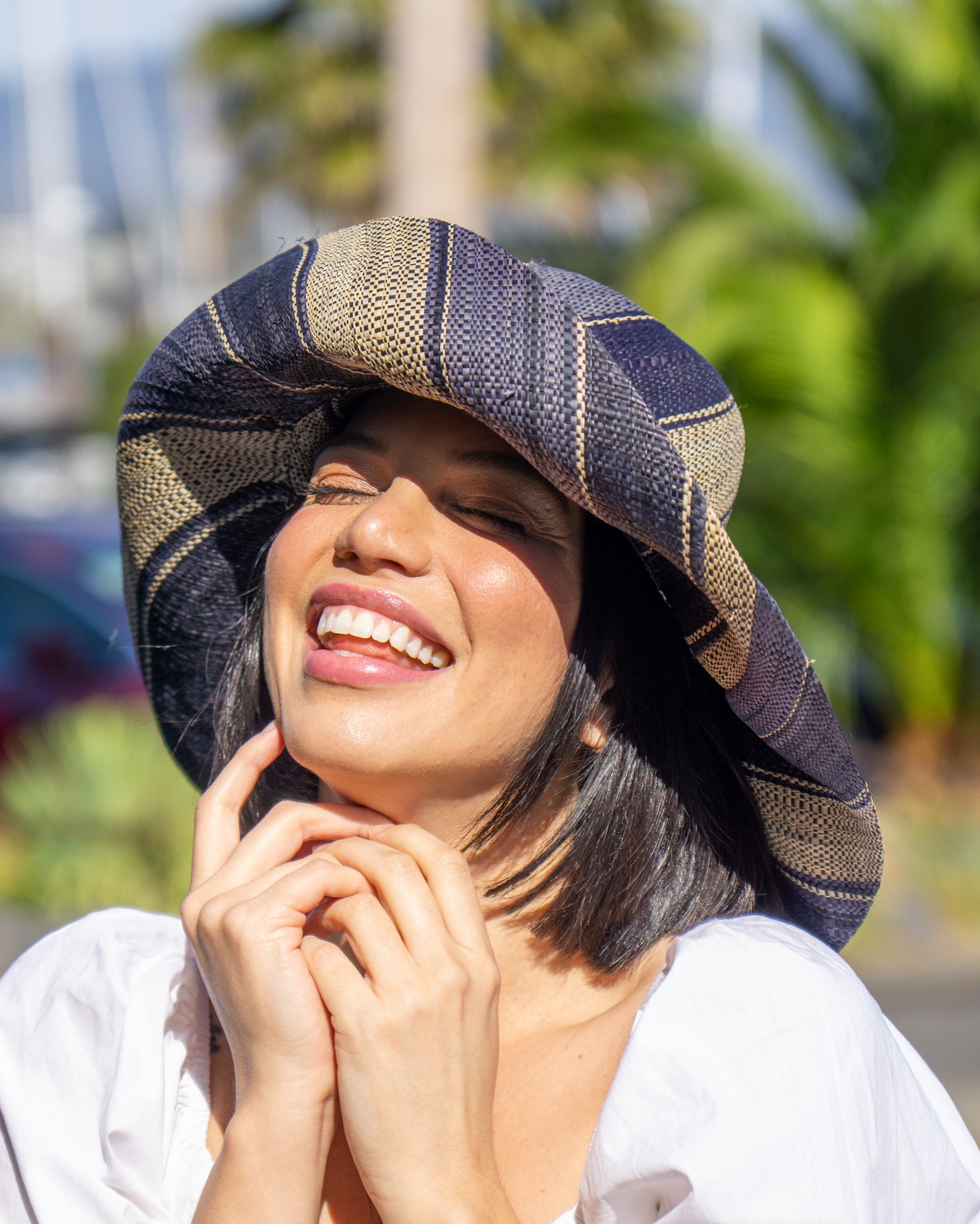 Model wearing Monica 5" Wide Brim Black Swirl Multicolor Stripe Pattern Packable Straw Sun Hat handmade loomed raffia in multi width bands of black, grey, and natural straw color create a striped swirl pattern - Shebobo