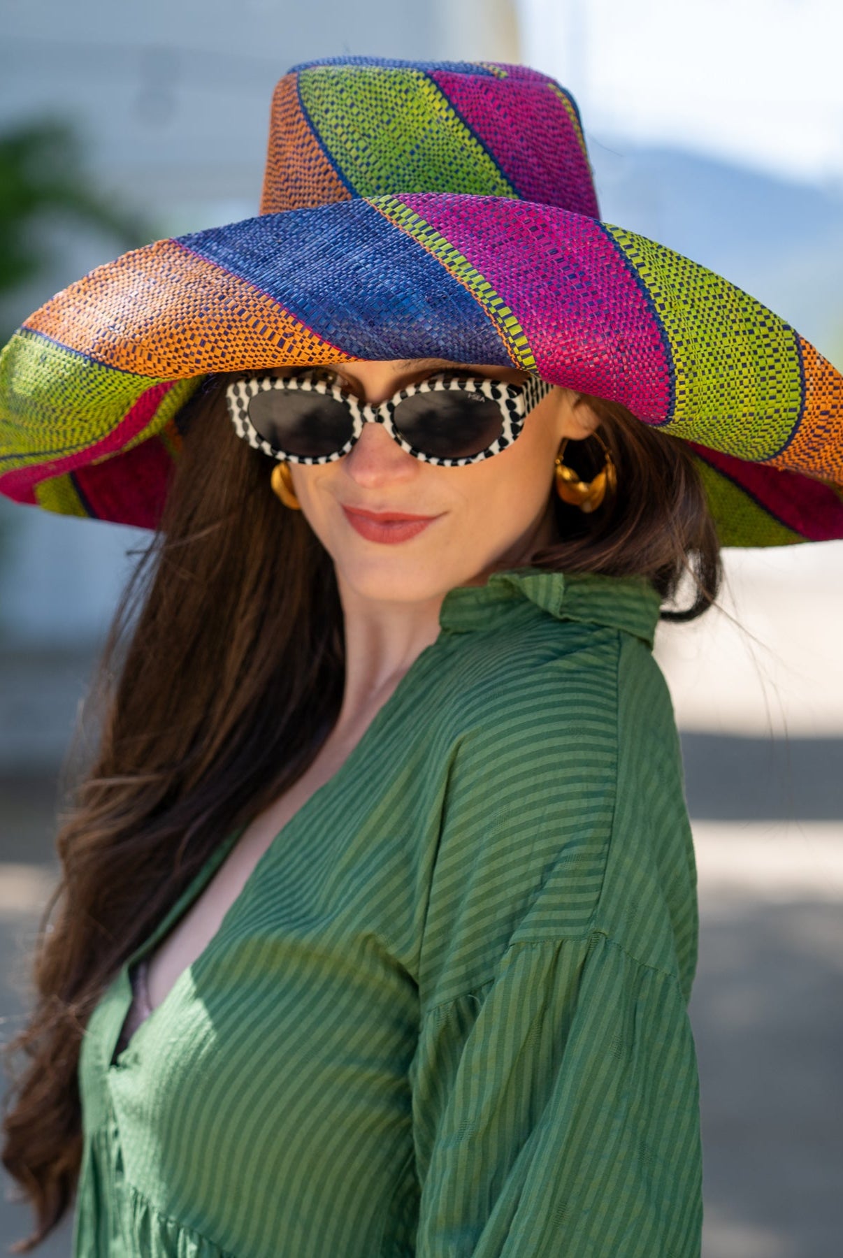 Model wearing Monica 7" Wide Brim Caribbean Swirl Multicolor Stripes Packable Straw Sun Hat Handmade loomed raffia in multi width bands of fuchsia pink, orange, dusk navy/dark/blue, and lime green create a swirl pattern - Shebobo