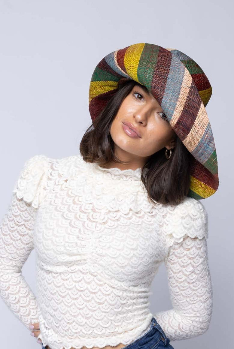 Model wearing Monica 5" & 7" Wide Brim Coral & Blue Swirl Multicolor Stripes Packable Straw Sun Hat Handmade loomed raffia in multi width bands of denim light/blue, whisky caramel/red/brown, black, dark forest/green, midori lime/green, and natural straw color create a swirl pattern - Shebobo