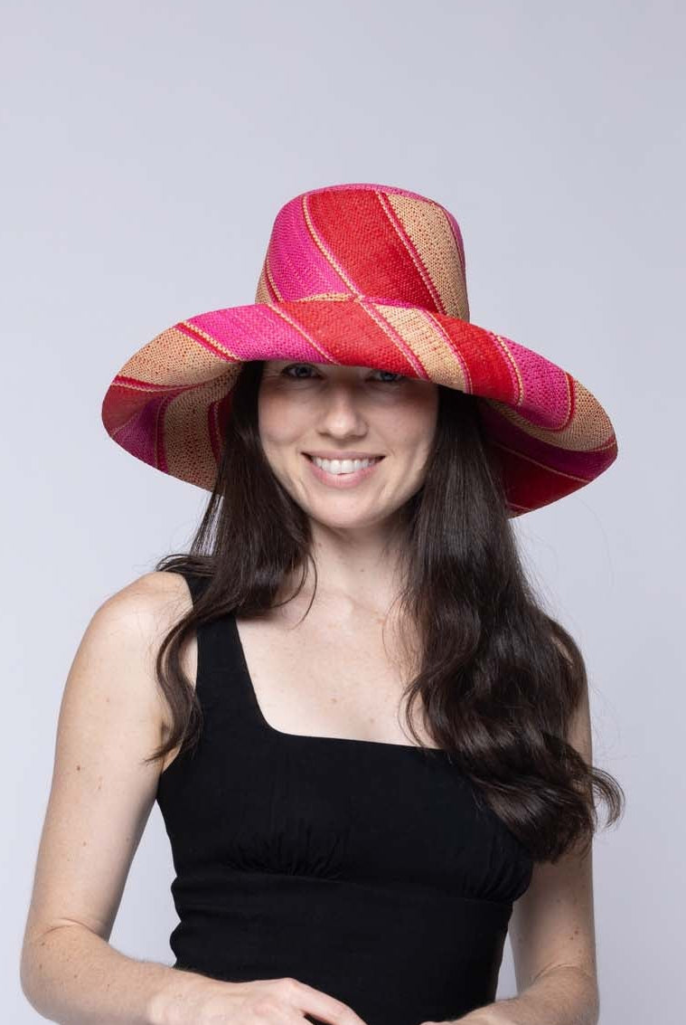 Model wearing Monica 5" & 7" Wide Brim Fuchsia & Red Swirl Multicolor Stripes Packable Straw Sun Hat Handmade loomed raffia in multi width bands of fuchsia hot/bright/pink, red, and natural straw color create a swirl pattern - Shebobo