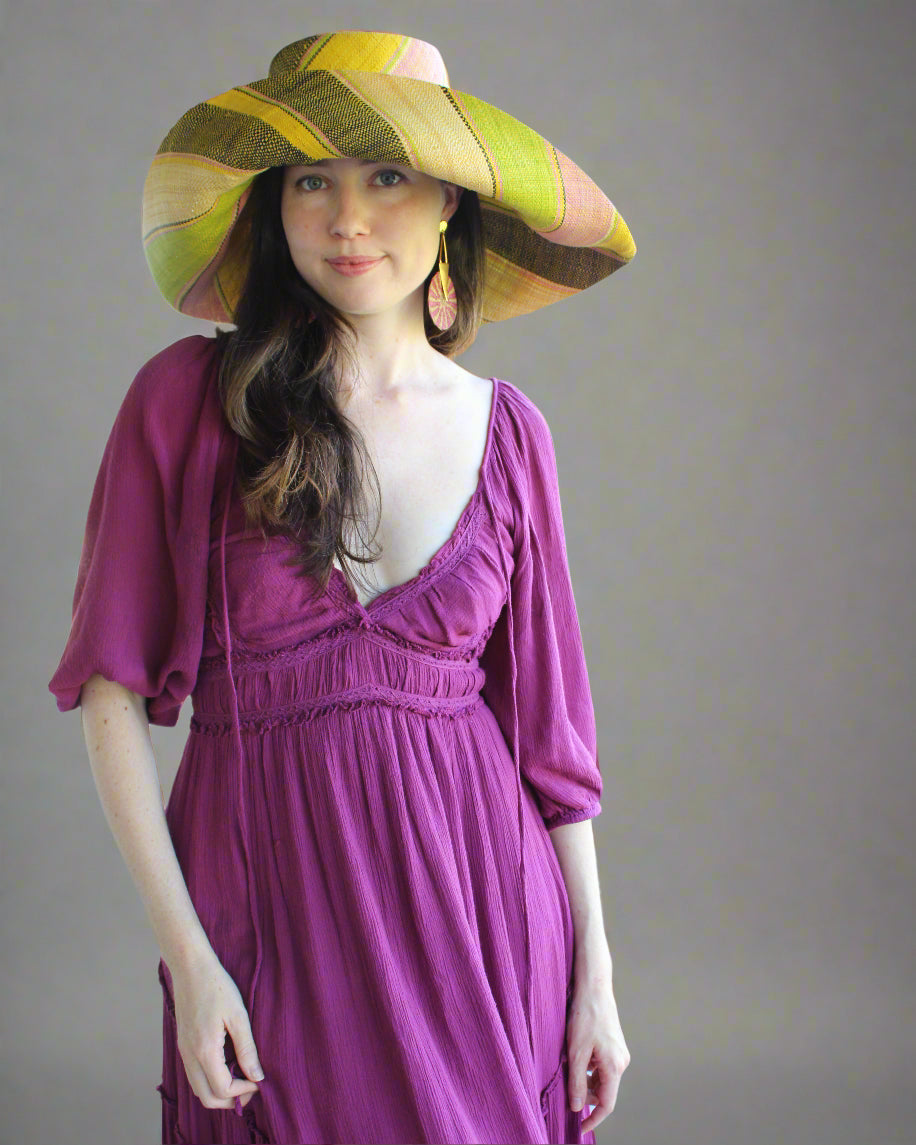 Model wearing Monica 7" Wide Brim Lemonade Swirl Multicolor Stripes Packable Straw Sun Hat Handmade loomed raffia in multi width bands of yellow, wisteria light/purple/pink, midori lime/green, black, natural straw color etc. create a swirl pattern - Shebobo