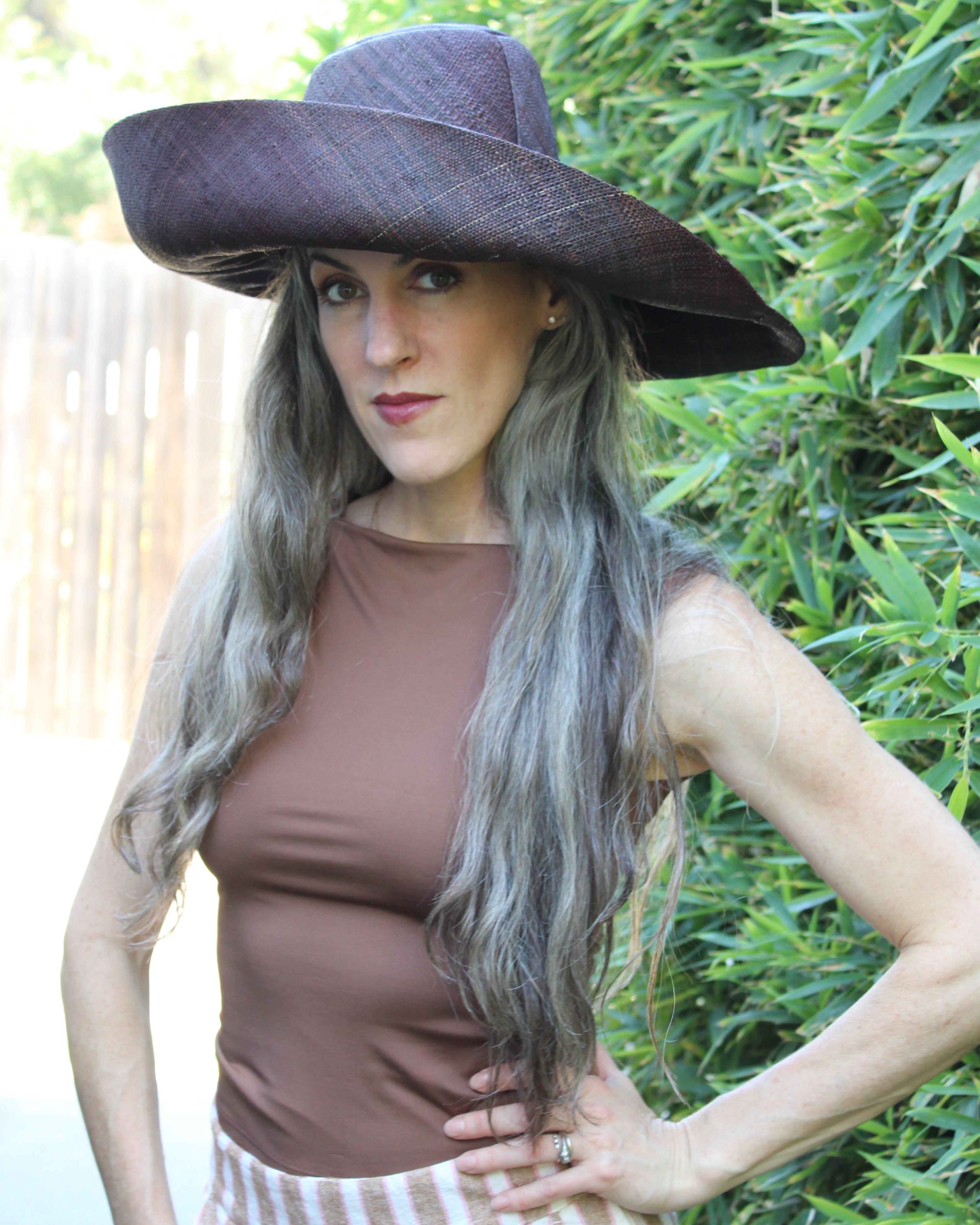 Model wearing Monica 7" Wide Brim Mocha Packable Straw Sun Hat handmade loomed raffia in a solid hue of mocha chocolate/dark/brown lightweight malleable flexible sun protection hat - Shebobo
