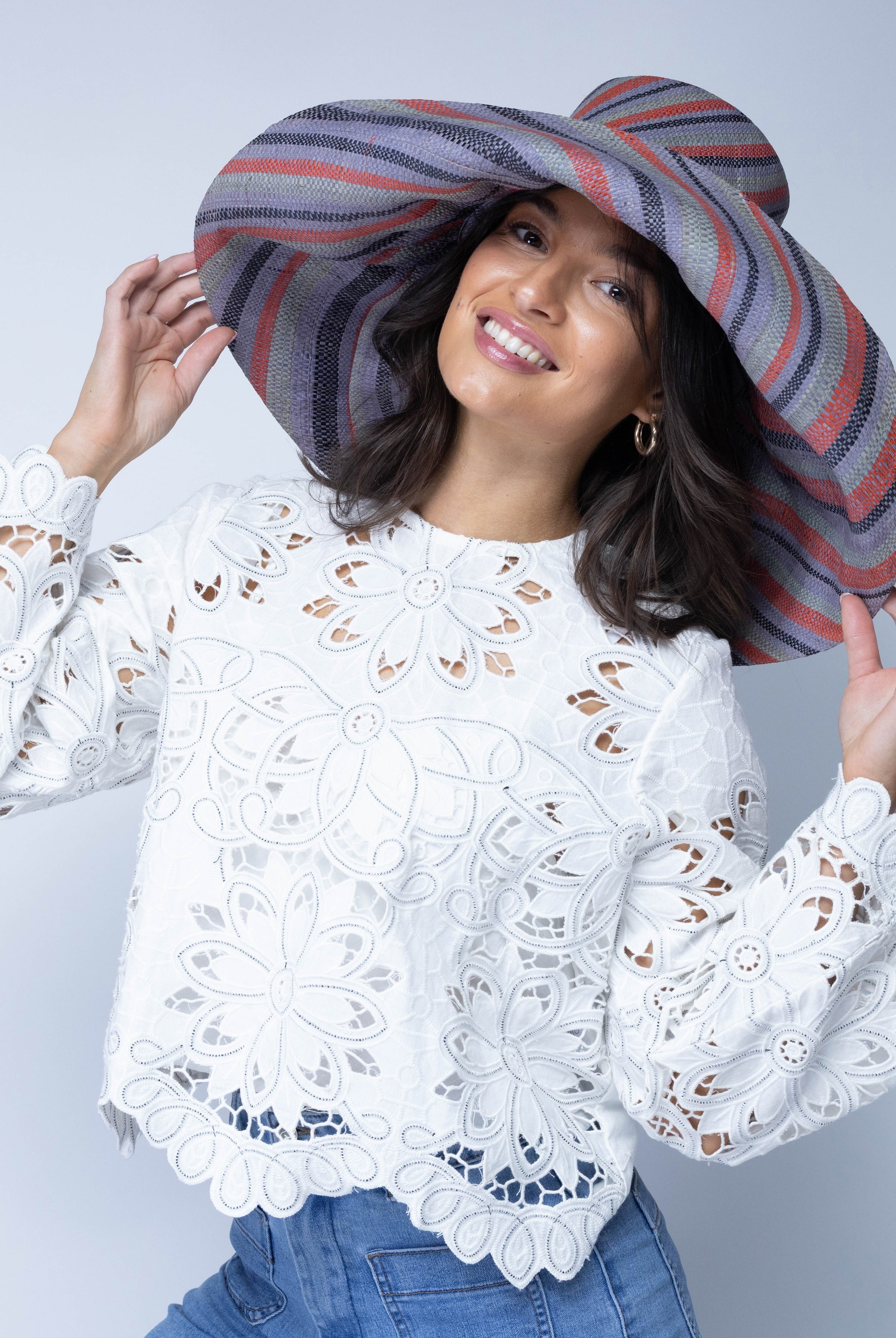 Model wearing Monica 7" Wide Brim Mulberry Swirl Multicolor Stripes Packable Straw Sun Hat handmade loomed raffia in bands of red, denim retro/light/blue, black, seafoam light/blue/green stripes create a swirl pattern - Shebobo