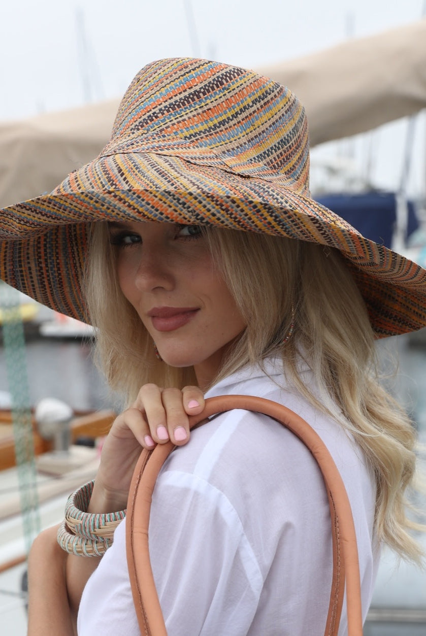 Model wearing Monica 5" Wide Brim Blush Multi Melange Packable Straw Sun Hat handmade loomed raffia multicolor heathered swirl pattern of orange, blush pink, natural, blue, brown, yellow, etc. - Shebobo
