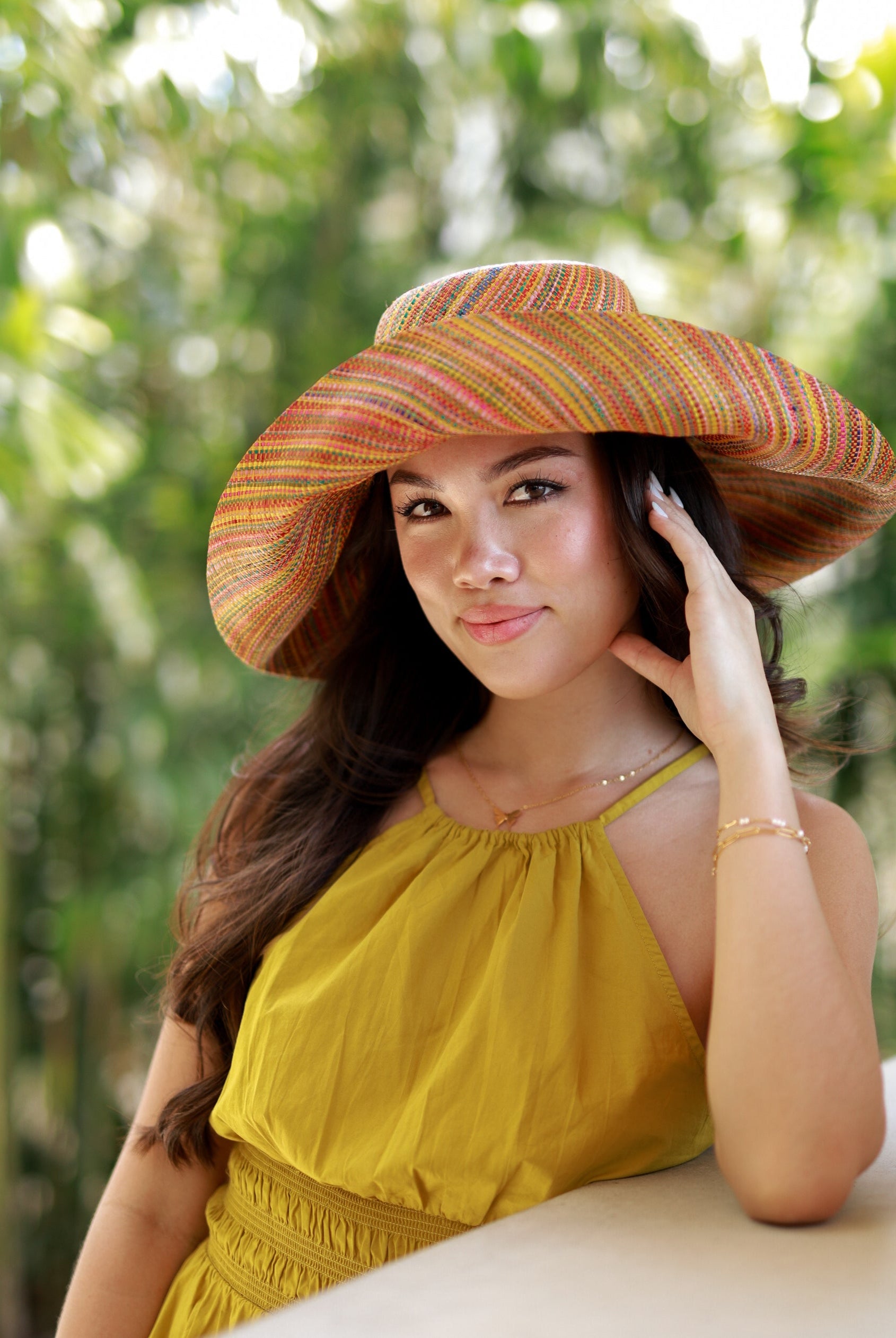 Model wearing Monica 5" Wide Brim Saffron Multi Melange Packable Straw Sun Hat handmade loomed raffia heather swirl pattern of saffron yellow, orange, red, bordeaux, green, pink, blue, etc. - Shebobo