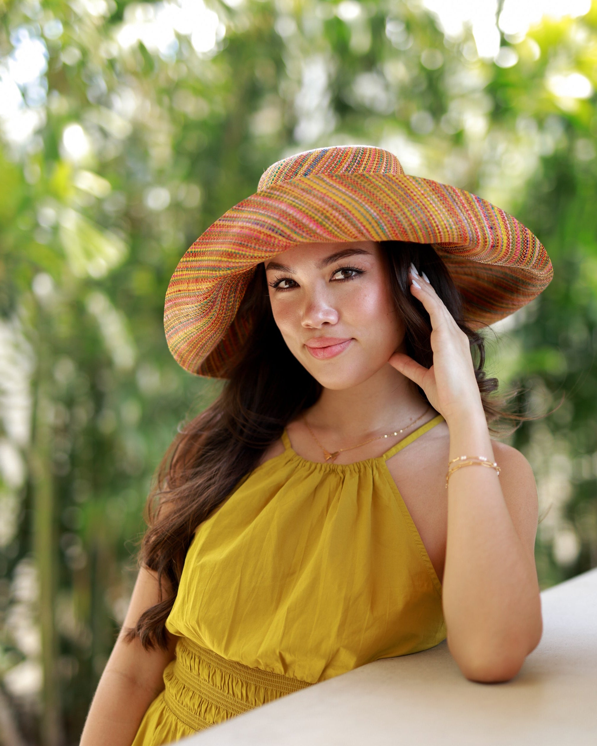 Model wearing Monica 5" Wide Brim Saffron Multi Melange Packable Straw Sun Hat handmade loomed raffia heather swirl pattern of saffron yellow, orange, red, bordeaux, green, pink, blue, etc. - Shebobo