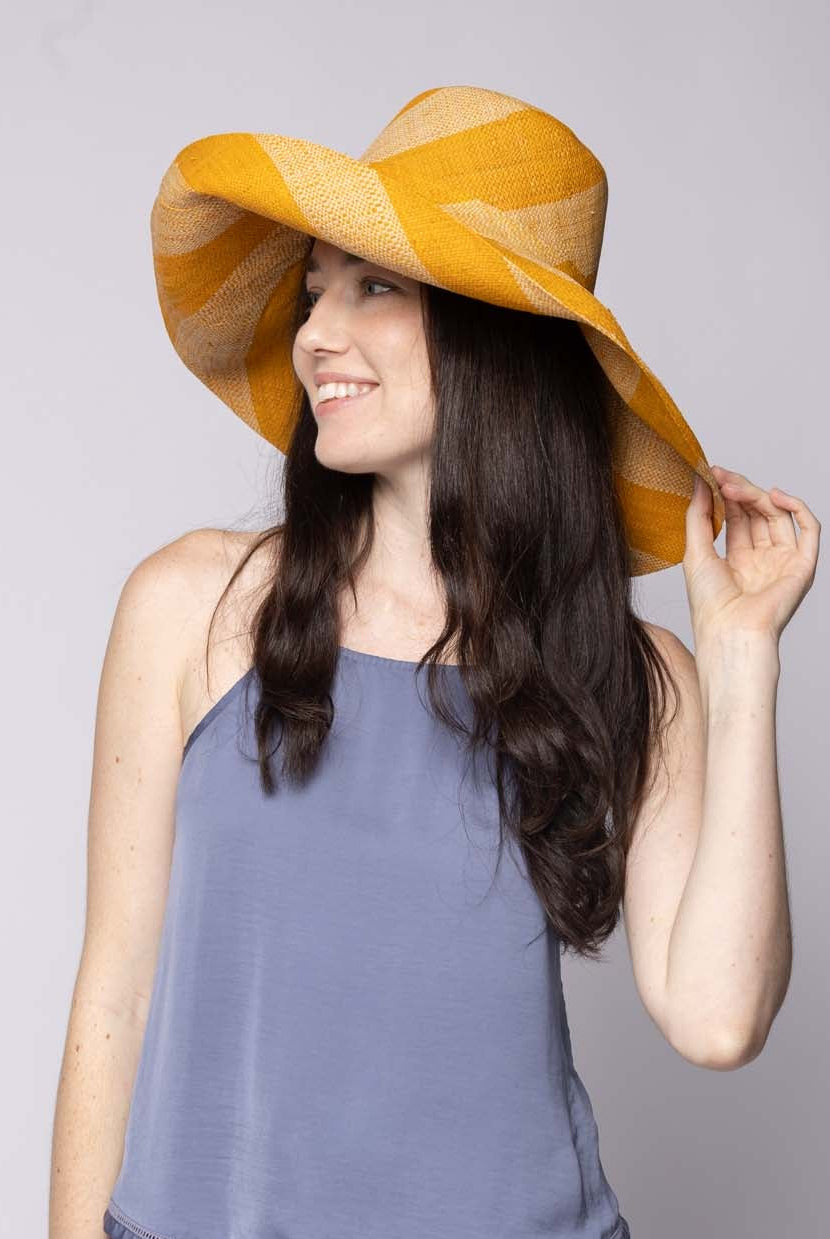 Model wearing Monica 5" & 7" Wide Brim Saffron & Natural Stripe Multicolor Stripes Packable Straw Sun Hat Handmade loomed raffia in even width bands of saffron yellow/orange, and natural straw color create a swirl pattern - Shebobo